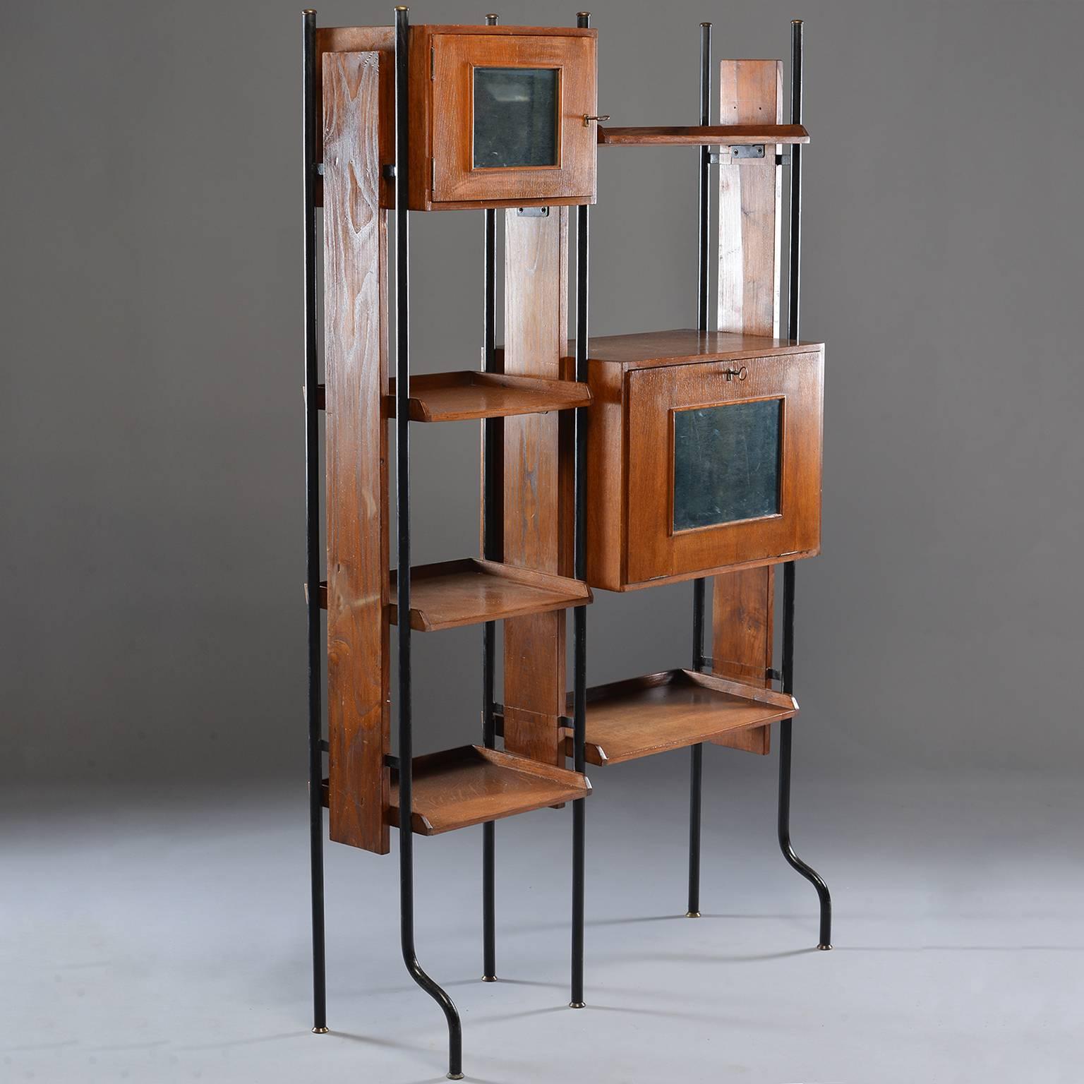 Small Italian etagere in manner of Vittorio Dassi features ebonized metal frame with contrasting wood shelves, circa 1960. Top compartment has working skeleton key lock and mirrored panel on door. Larger compartment is a drop down door that