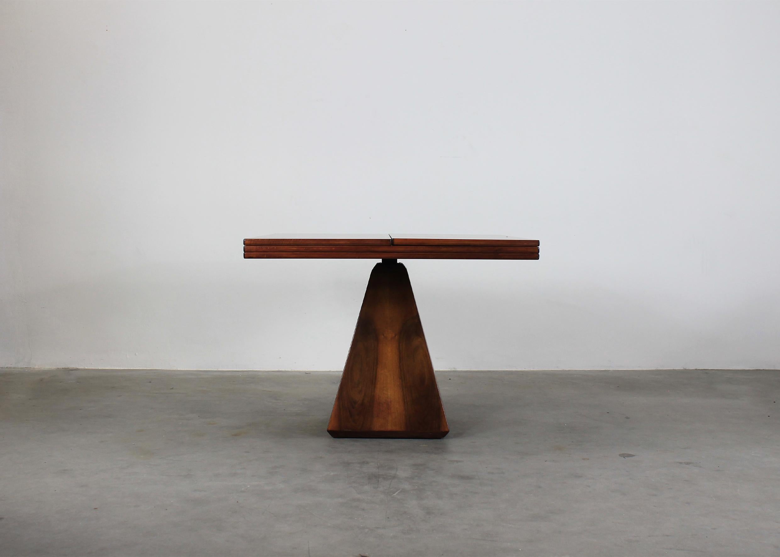 Extendable Chelsea dining table with a square tabletop and a pyramidal base entirely made in walnut wood and metal details. 

It was designed by Vittorio Introini and produced by Saporiti during the 1960s.

The tabletop can be opened up and