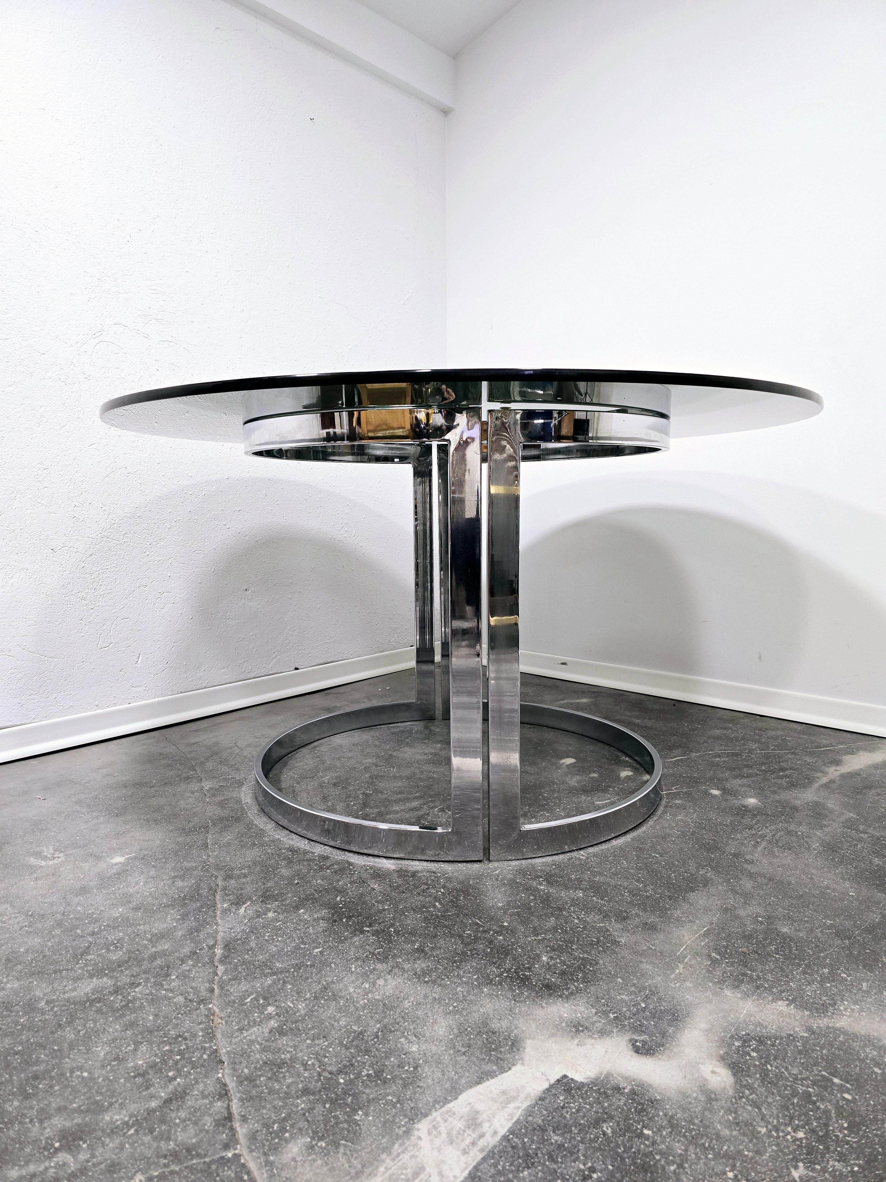 Mesa de comedor de cristal diseñada por Vittorio Introini, fabricada en Italia en la década de 1970. 

La mesa tiene un tablero de cristal ahumado de 15 mm de grosor. 

La estructura de soporte es de metal cromado, y tiene dos patas que se unen para