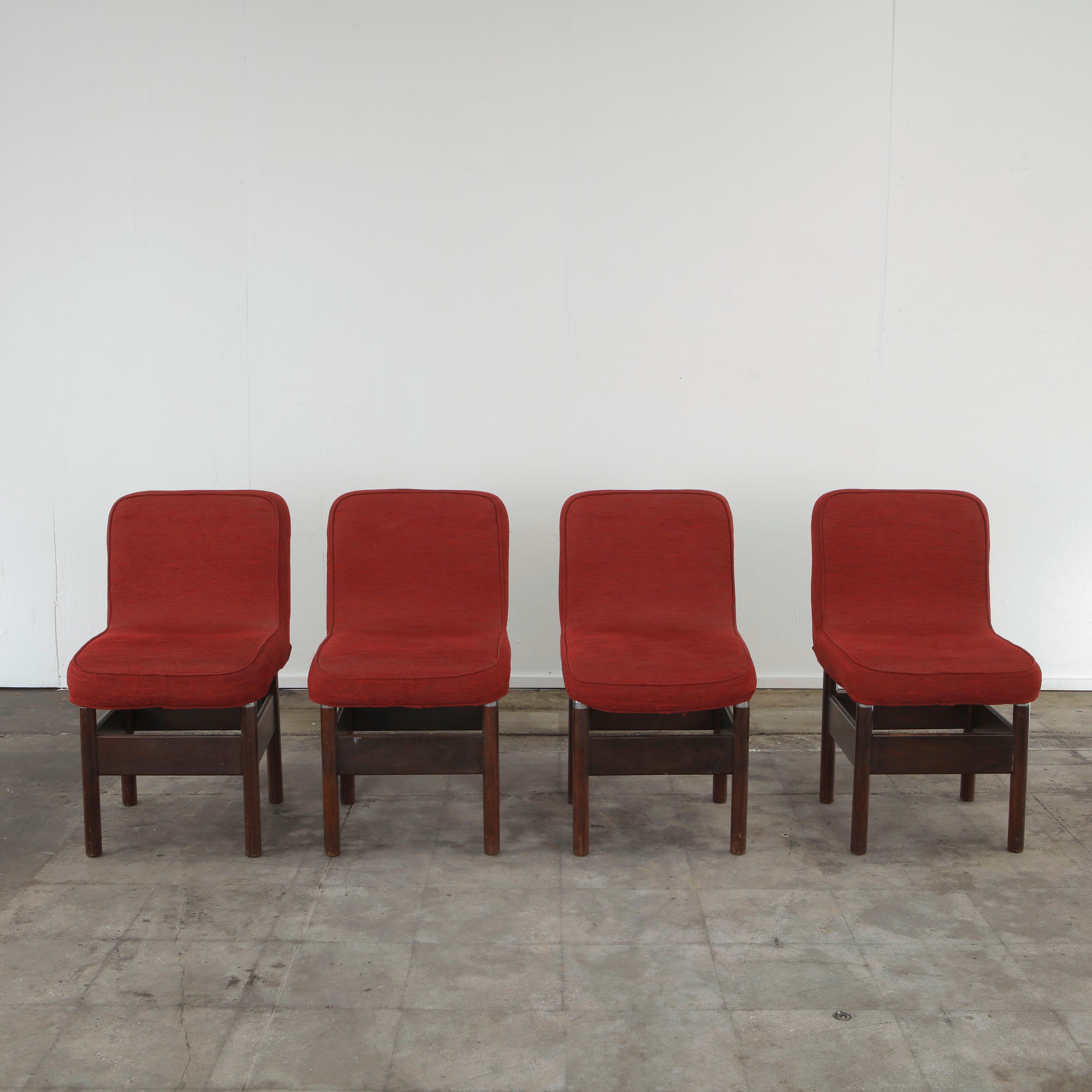 Set of four Italian dining chairs from the 1960s featuring clean, architectural lines and refined proportions typical of the Italian modernist era. Each chair has a low, curved backrest and a thick, comfortable seat, both upholstered in a rich