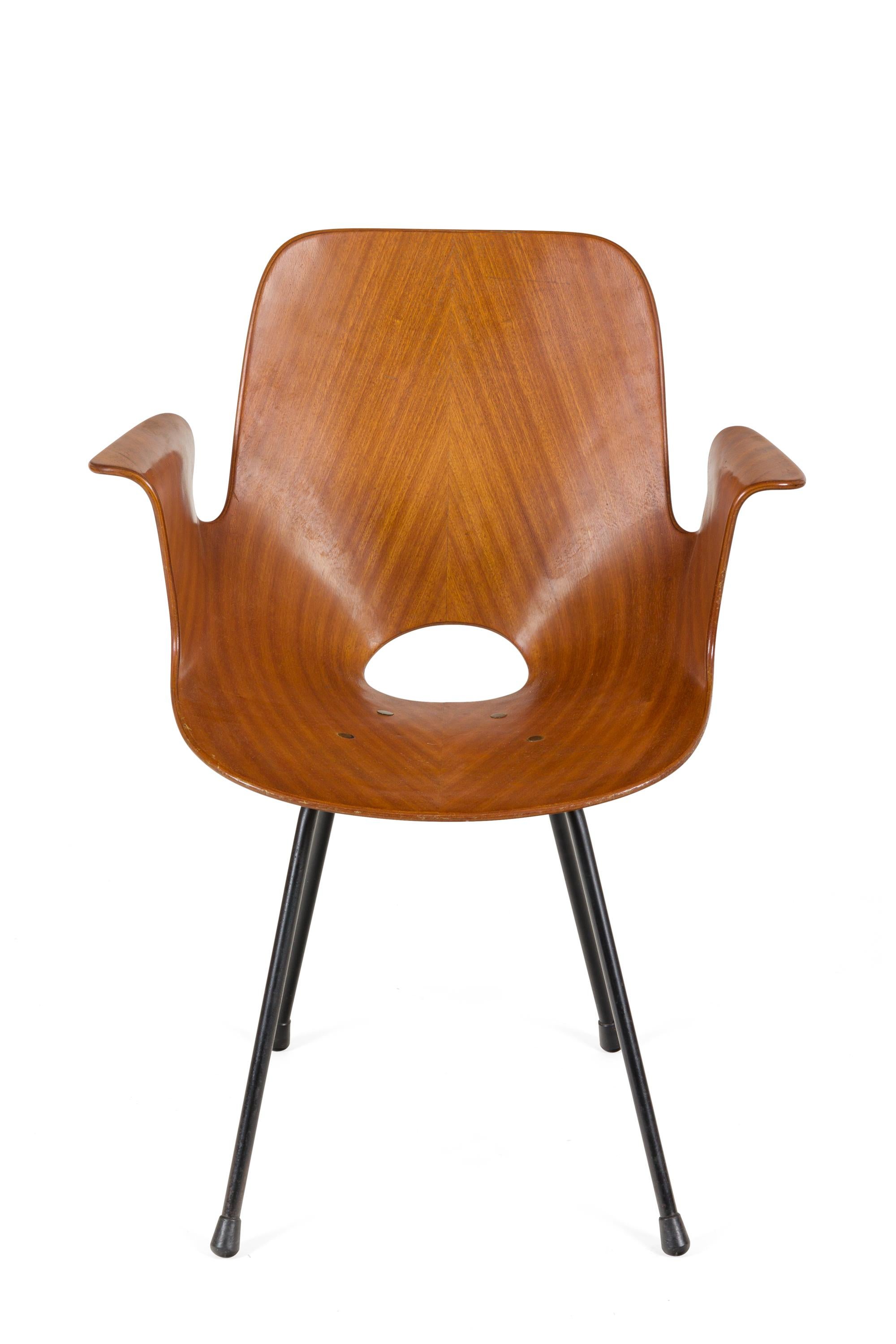 The Medea chairs by Nobili are an iconic design from the 1950s. More commonly found without the armrests, these chairs add an extra element of comfort while maintaining the unique design. They are made of molded plywood with a mahogany veneer. The