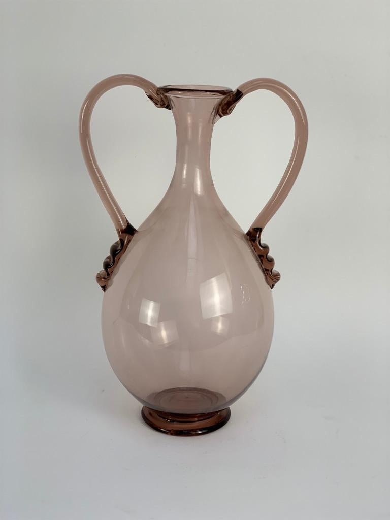 Light amethyst-colored blown Murano glass vase, designed by Vittorio Zecchin in 1921 and made by Venini Murano.
Small mouth that widens towards the base with a pot-bellied body, wide handles decorated with 