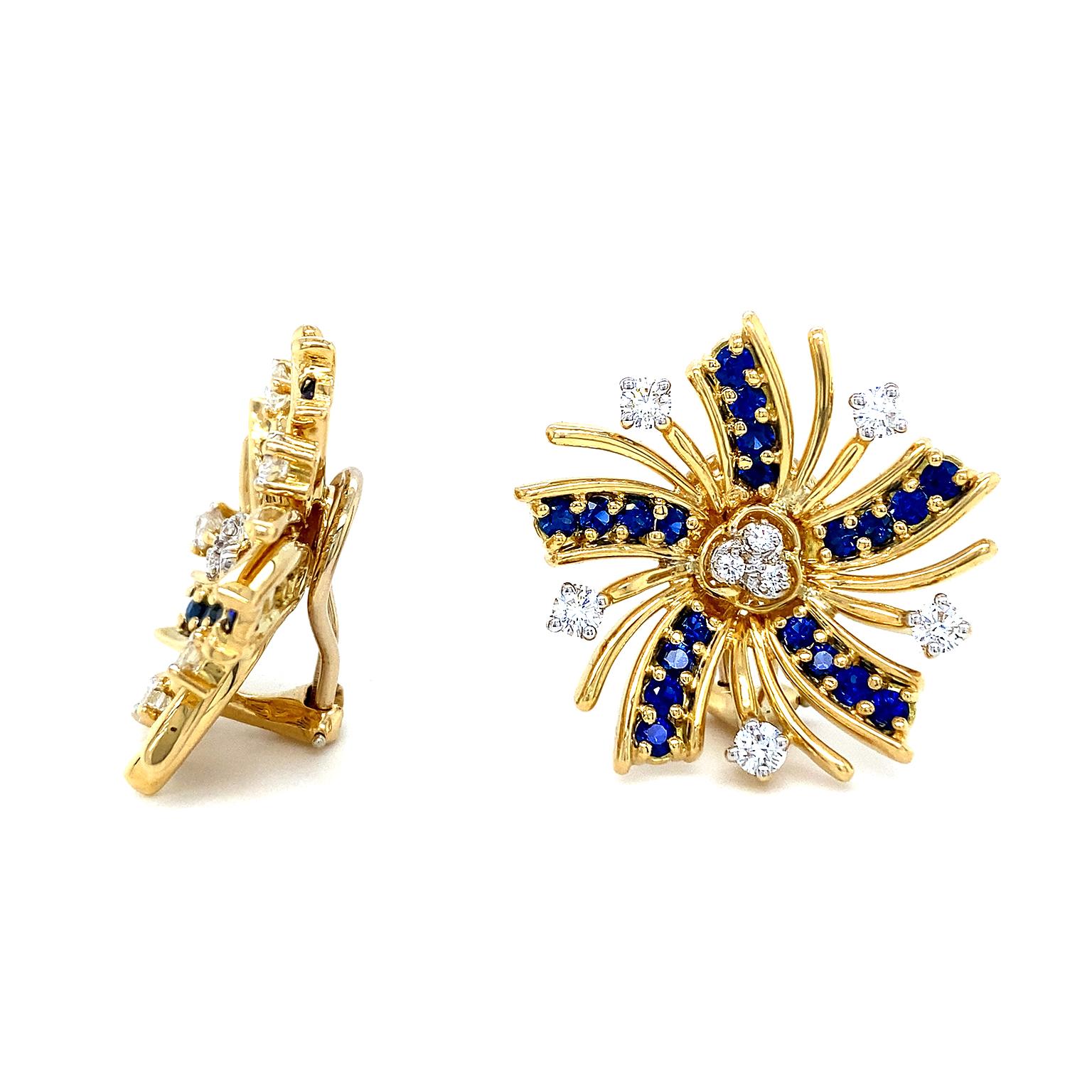 Diamonds and sapphires join gold for festive radiance. In the center of the design are 3 brilliant cut diamonds encrusted in 18k yellow gold. 5 curved beams of sapphires pave set in gold emit outward. In between each beam are 2 slender gold strands,