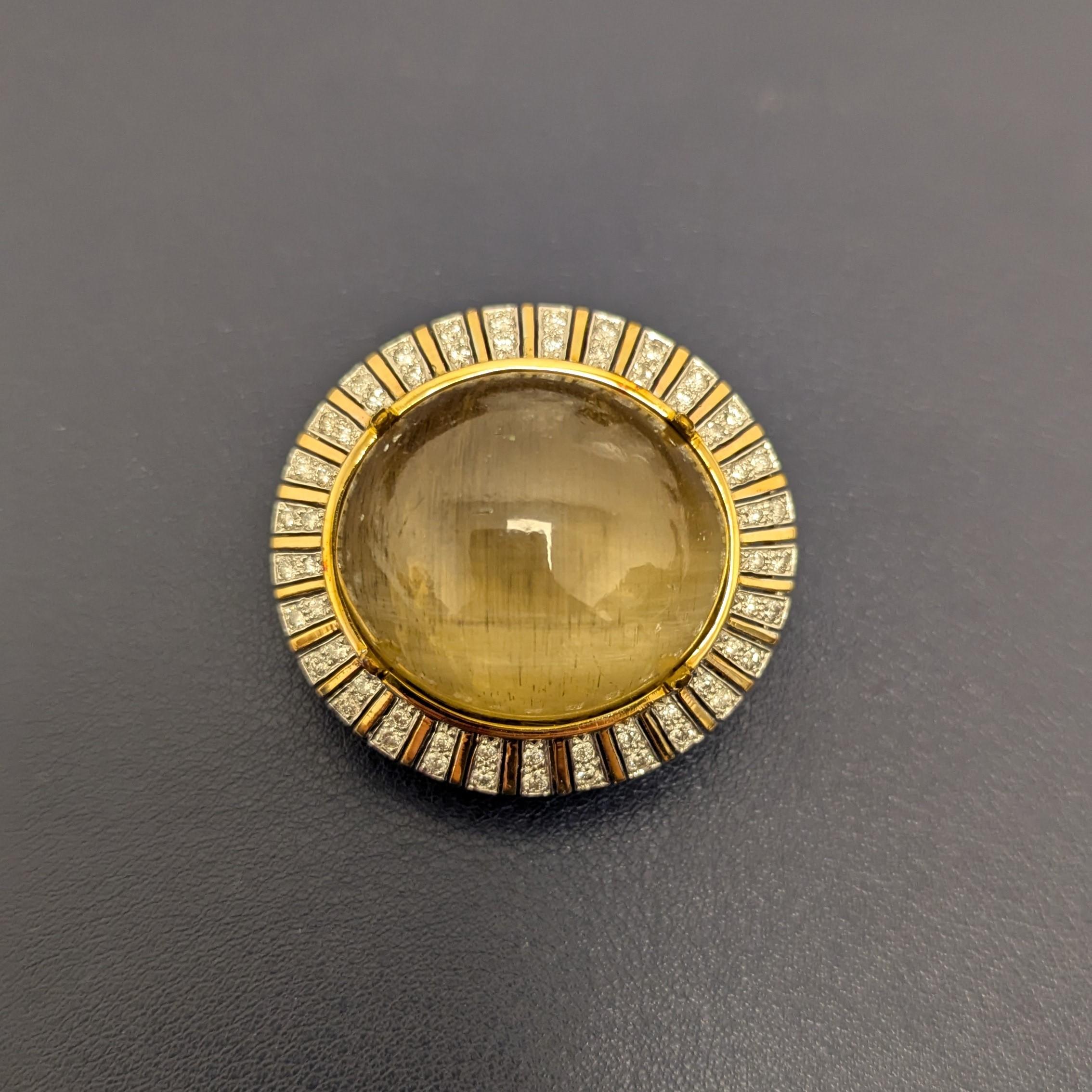 This brooch features a show-stopping oval cats eye chrysoberyl cabochon, encircled within a sea of single-cut diamonds estimated to weigh around 2.00 carats. All meticulously mounted in 14k yellow gold.