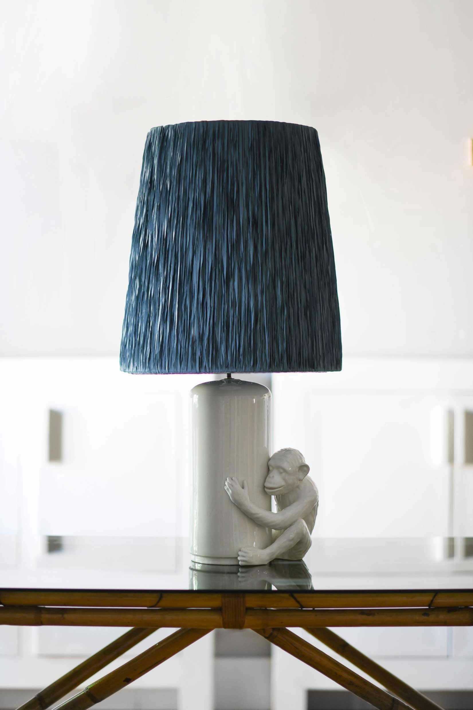 Vivai del Sud table lamp in white glazed ceramic with monkey-shaped iconic sculpture and raffia lampshade. 
Made in Italy in the 1970s this is a very rare table lamp produced by Vivai del SUD, a family-run company, which between the seventies and