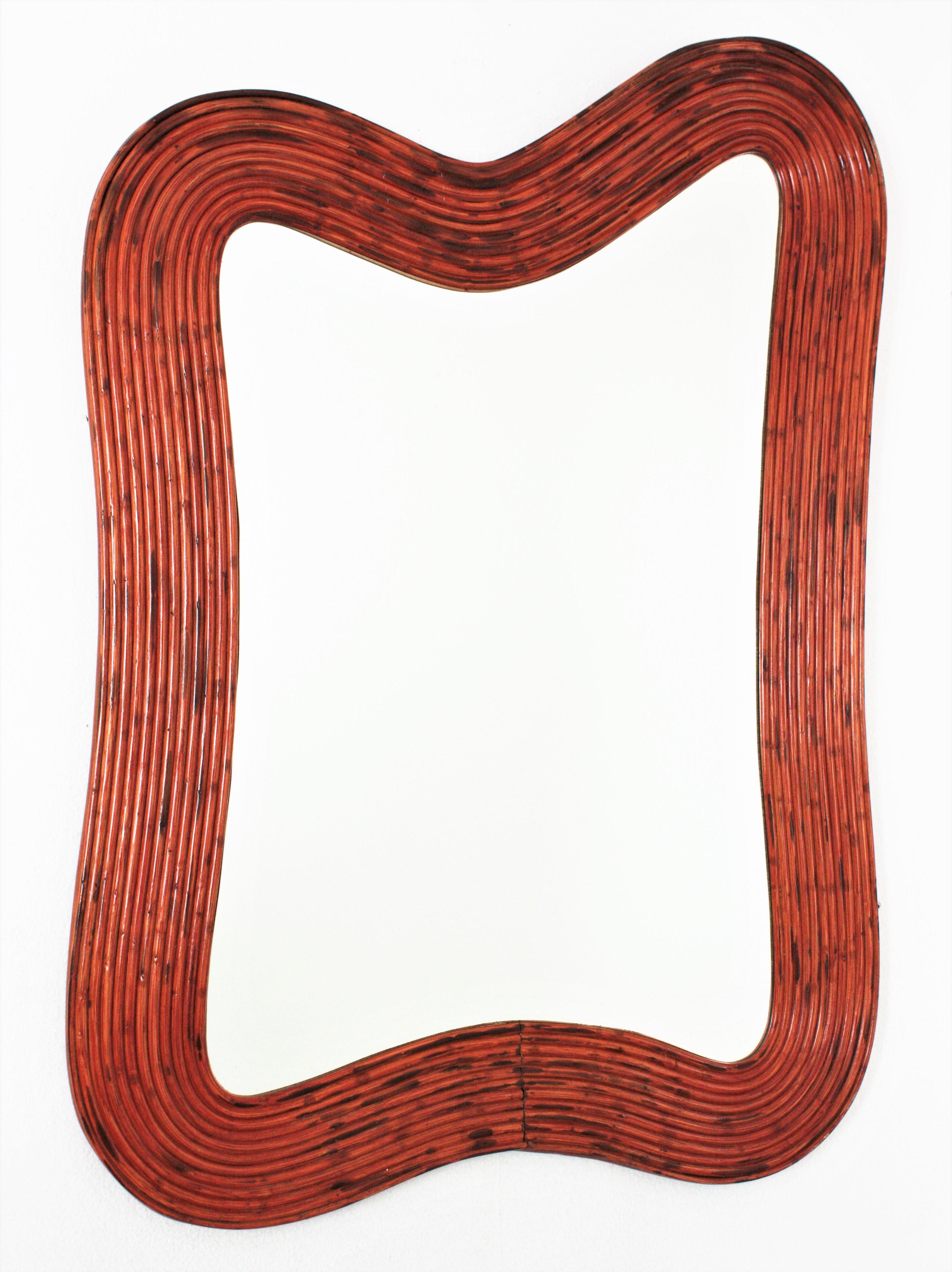 Eye-caching organic shaped moderist mirror handcrafted in rattan. Attributed to Vivai del Sud. Italy, 1960s.
This mirror features a finely executed frame with organic design made of 12 layers of rattan canes.
To be used as wall mirror on a