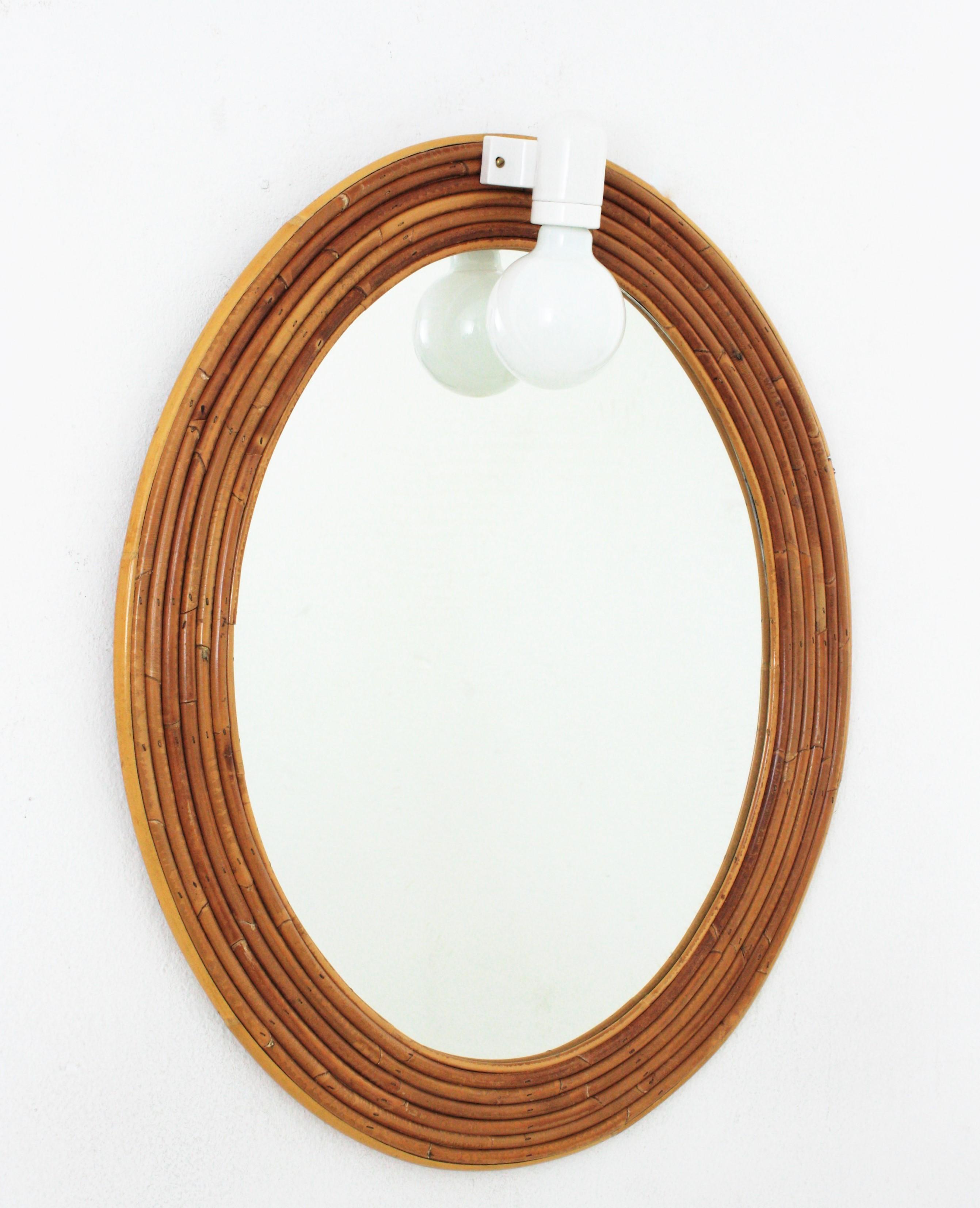 Eye-caching Organic Modern oval handcrafted in rattan / pencil reed. Attributed to Vivai del Sud. Italy, 1960s.
This mirror features a finely executed oval frame made of layers of rattan canes. It has a light on the top.
As the original light