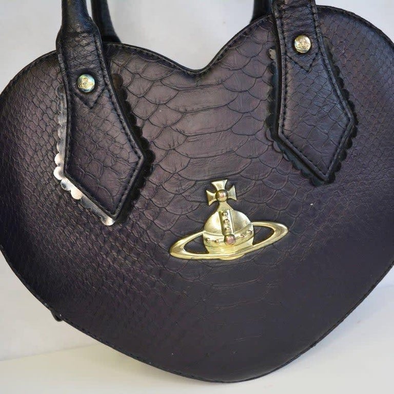 This Westwood Chancery Heart bag is perfect for summer. The bag is made in faux snakeskin with PVC and frill trim detail. The main compartment that is lined with Vivienne's Orb and star lining.

COLOR: Black 
MATERIAL: PVC
MEASURES: H 8” x L 4.5” x
