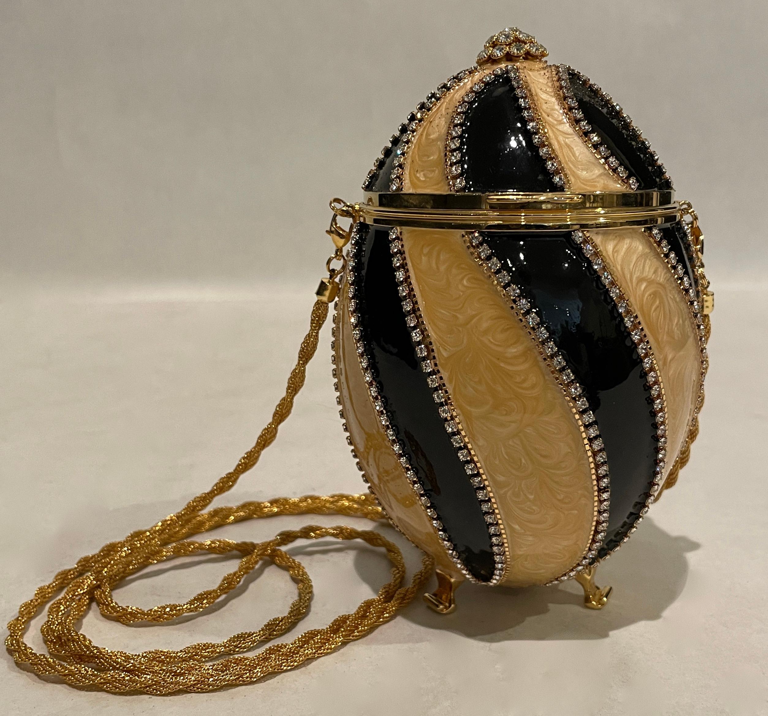 Cause a stir when carrying this exotic and luxurious Swarovski crystal with black and champagne enamel minaudiere! Vivian Alexander created the ostrich egg purse in 1990 and retired it in 2007. The enameled egg purse is made using techniques learned