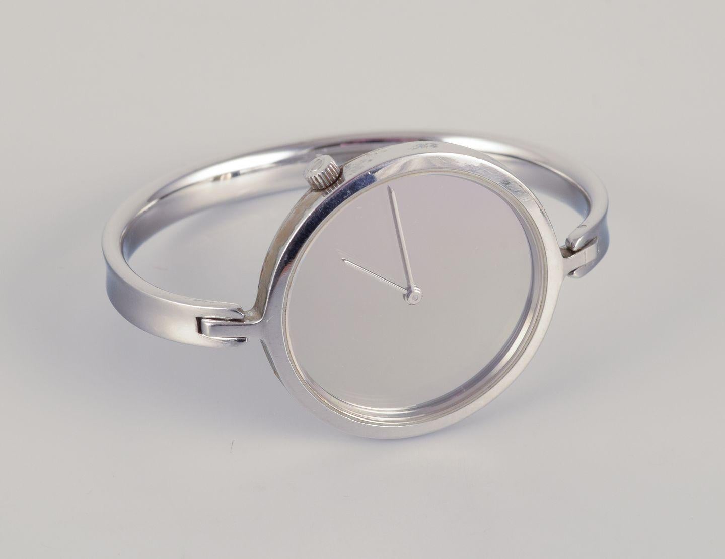 Vivianna Torun Bülow-Hübe para Georg Jensen, reloj de pulsera de acero.
Model 327. 
Movimiento de cuarzo.
Esfera plateada con agujas de acero. Grillete integrado. 
Datación: finales del siglo XX.
En buen estado con pequeños signos de