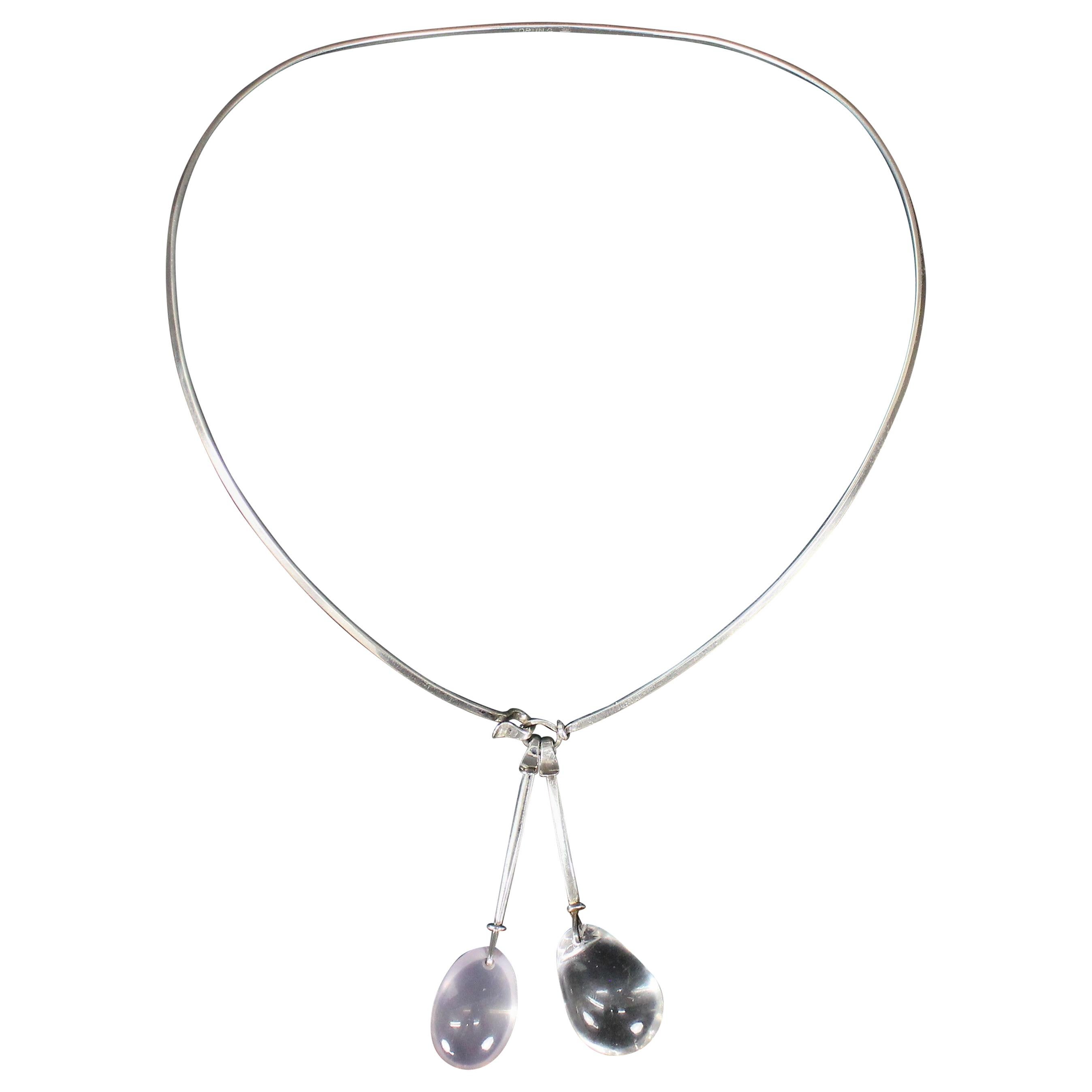 This necklace is made by herself in her own workshop way before she made these for Georg Jensen. 
Made in silver with two drop pendants, one cabochon-cut rose quartz, and one cabochon-cut rock crystal. 
All three parts are marked 