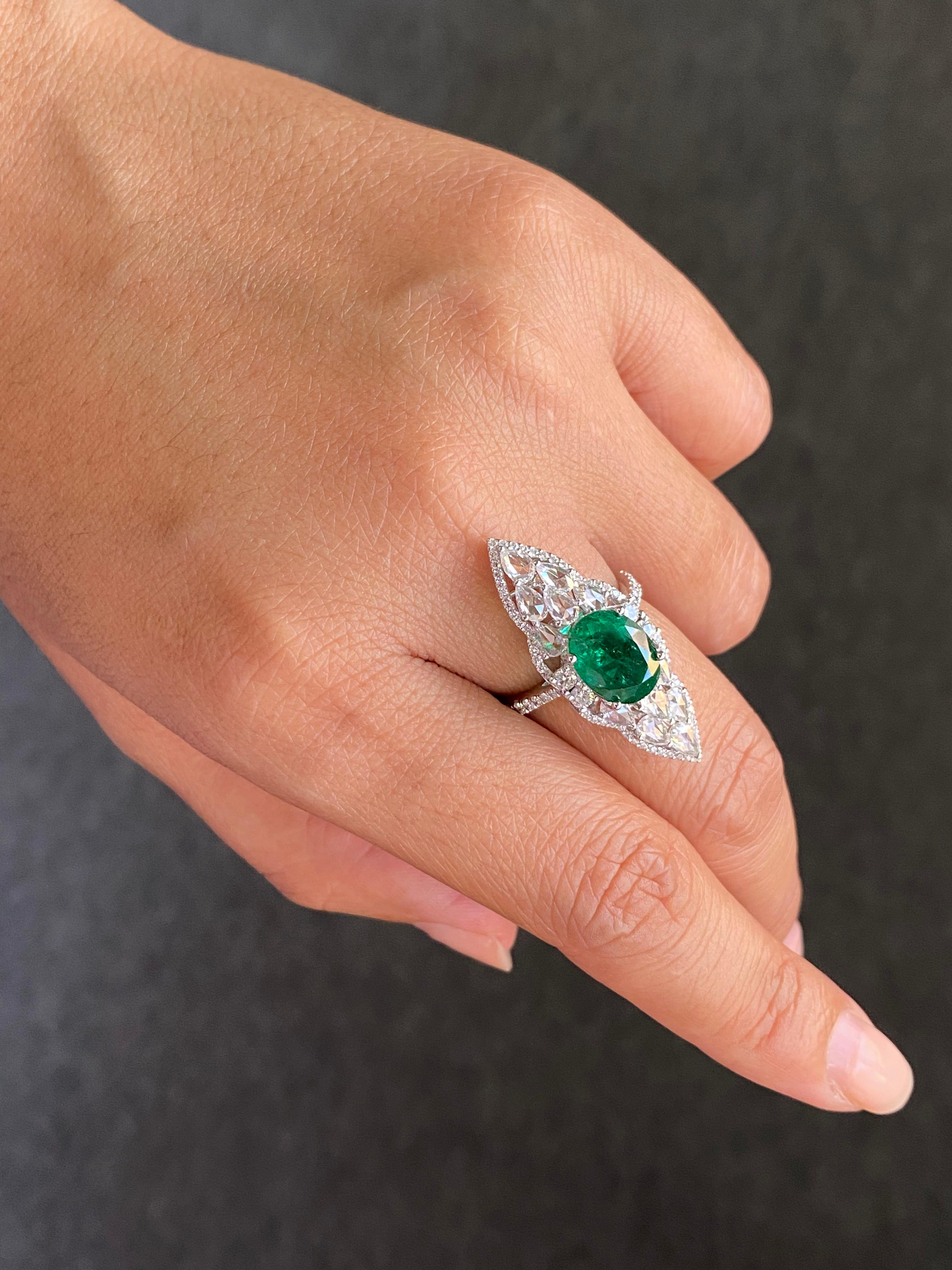The ring crafted in 18K white gold, at its heart, there is a vivid 3.11 carat oval emerald which steals the spotlight, radiating a vibrant green brilliance. 

Flanking the centerpiece are pear-shaped diamonds (1.15 carats) and an intricate halo of