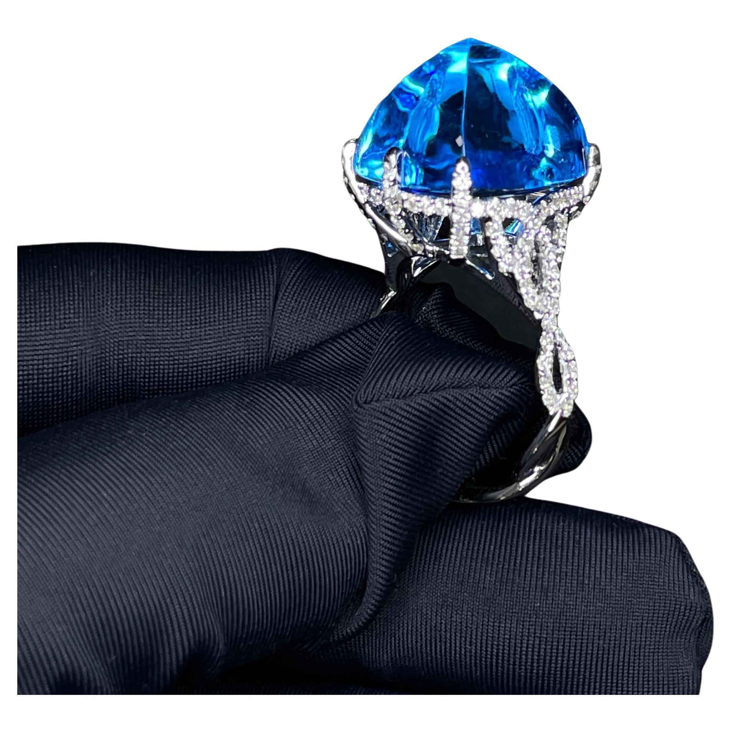 This is a Topaz Diamond ring in 18K White Gold. The whooping 24 CT Topaz is destined to be a show stopper. The sugar-loaf Topaz is being held by 6 Diamonds encrusted claws in a spiraling descending design, which makes it one of its kind. This is a
