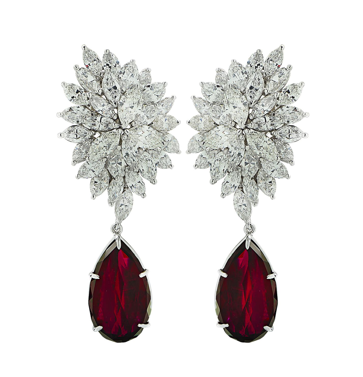 Sensational Vivid Diamonds dangle earrings crafted in 18 karat white gold, showcasing 2 exquisite pear cut, vivid crimson red tourmaline stones, accented by 56 marquise cut diamonds weighing 12.70 carats total, F-J color, VS clarity. They measure 2