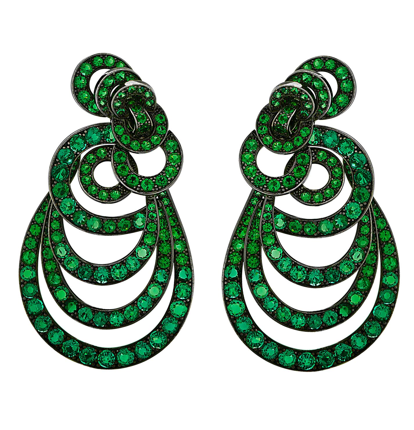 This unique pair of earrings fuse elegance and whimsical design. Set in 18 karat gold plated with black rhodium, showcasing 280 round cut emeralds, weighing approximately 18 carats. Framed with layers of circles cascading into ovals, arranged to
