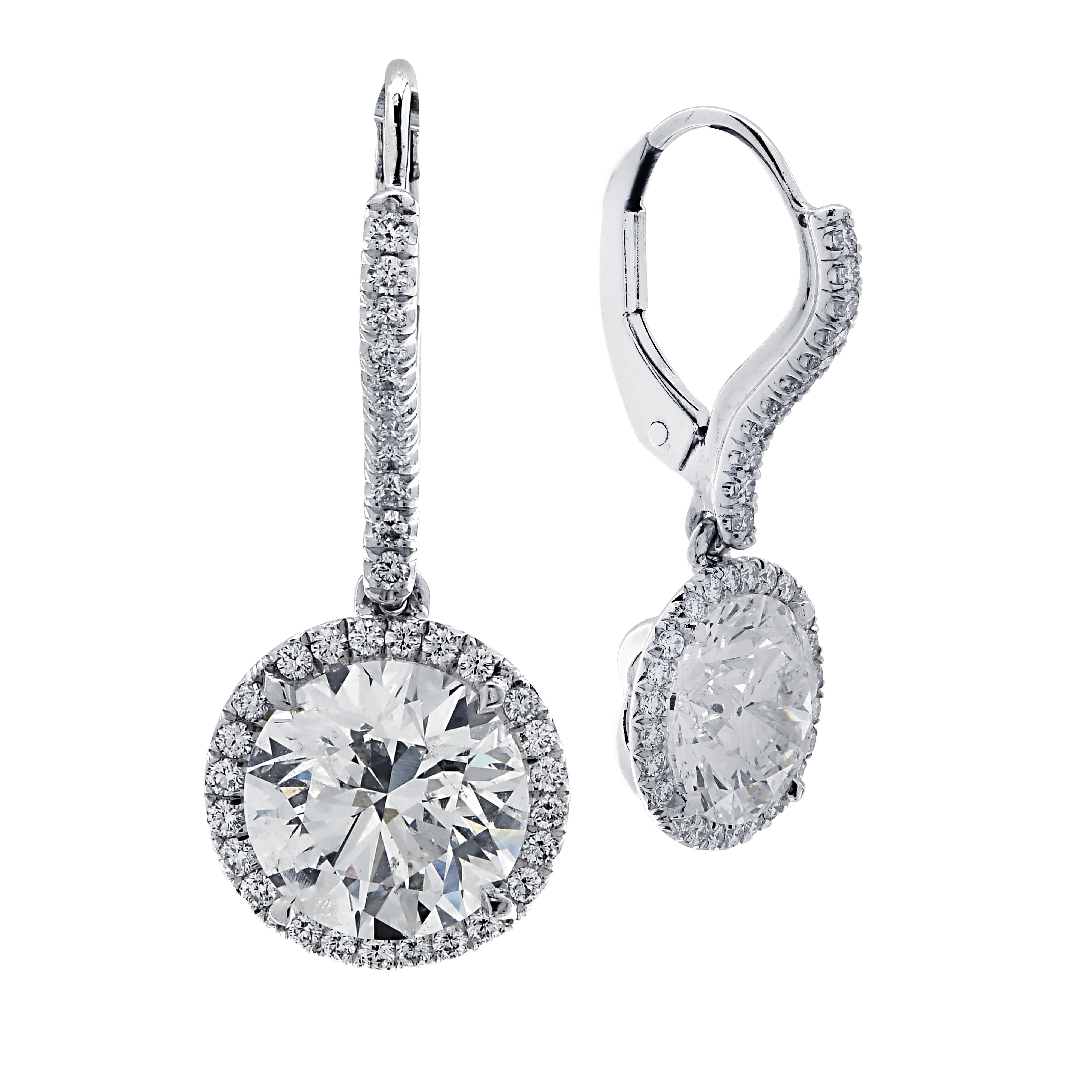 Sensational Vivid Diamonds dangle earrings crafted in 18 karat white gold showcasing two round brilliant cut diamonds weighing 3 carats total, I color, I1 clarity framed in diamond halos and suspended from diamond encrusted posts. 70 round brilliant