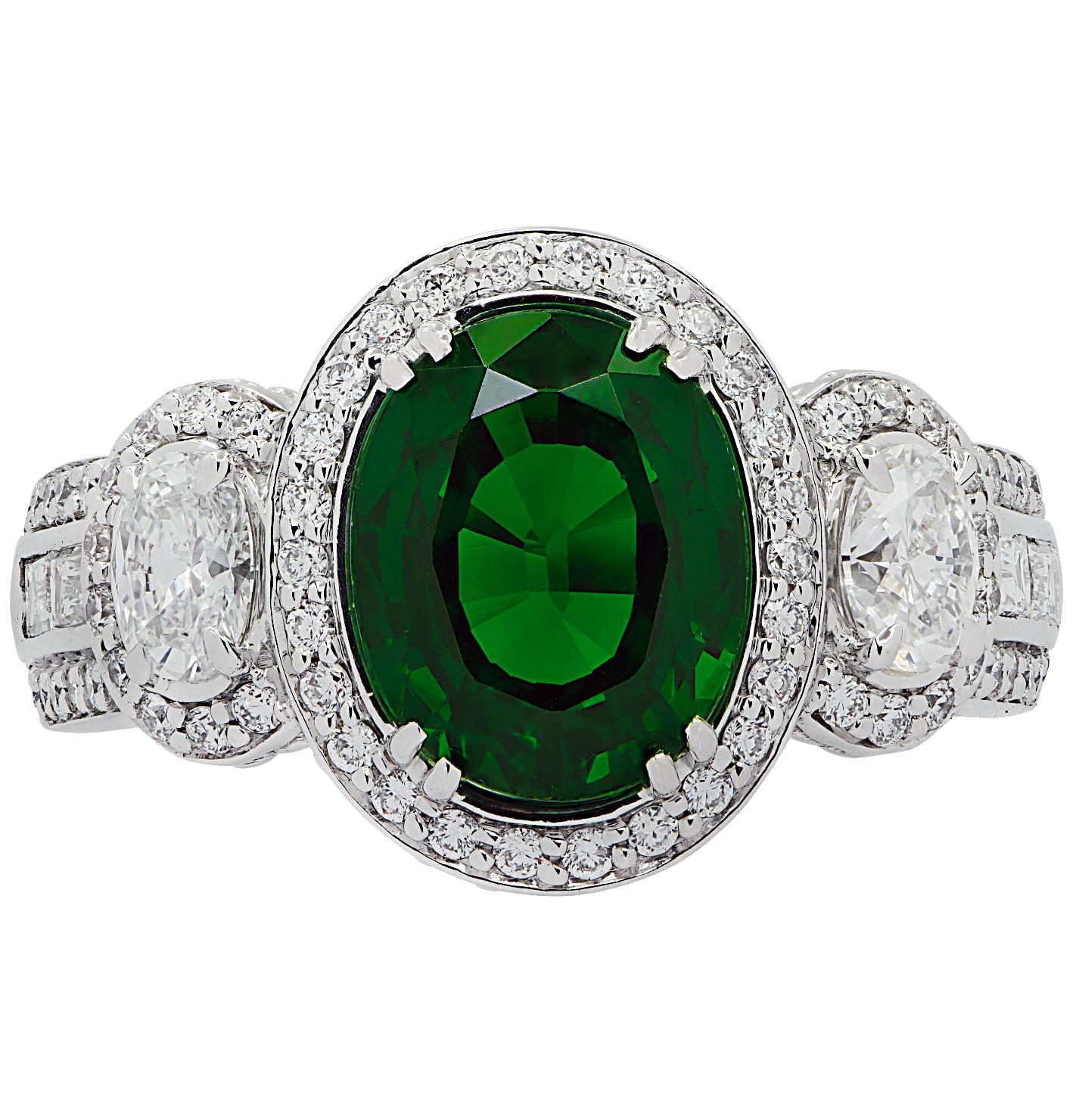 Spectacular Vivid Diamonds ring crafted in 18 karat white gold showcasing a stunning rich green oval cut Tsavorite weighing 3.38 carats, accented by two round oval cut diamonds weighing approximately .40 carats total, G color, VS clarity, and 84