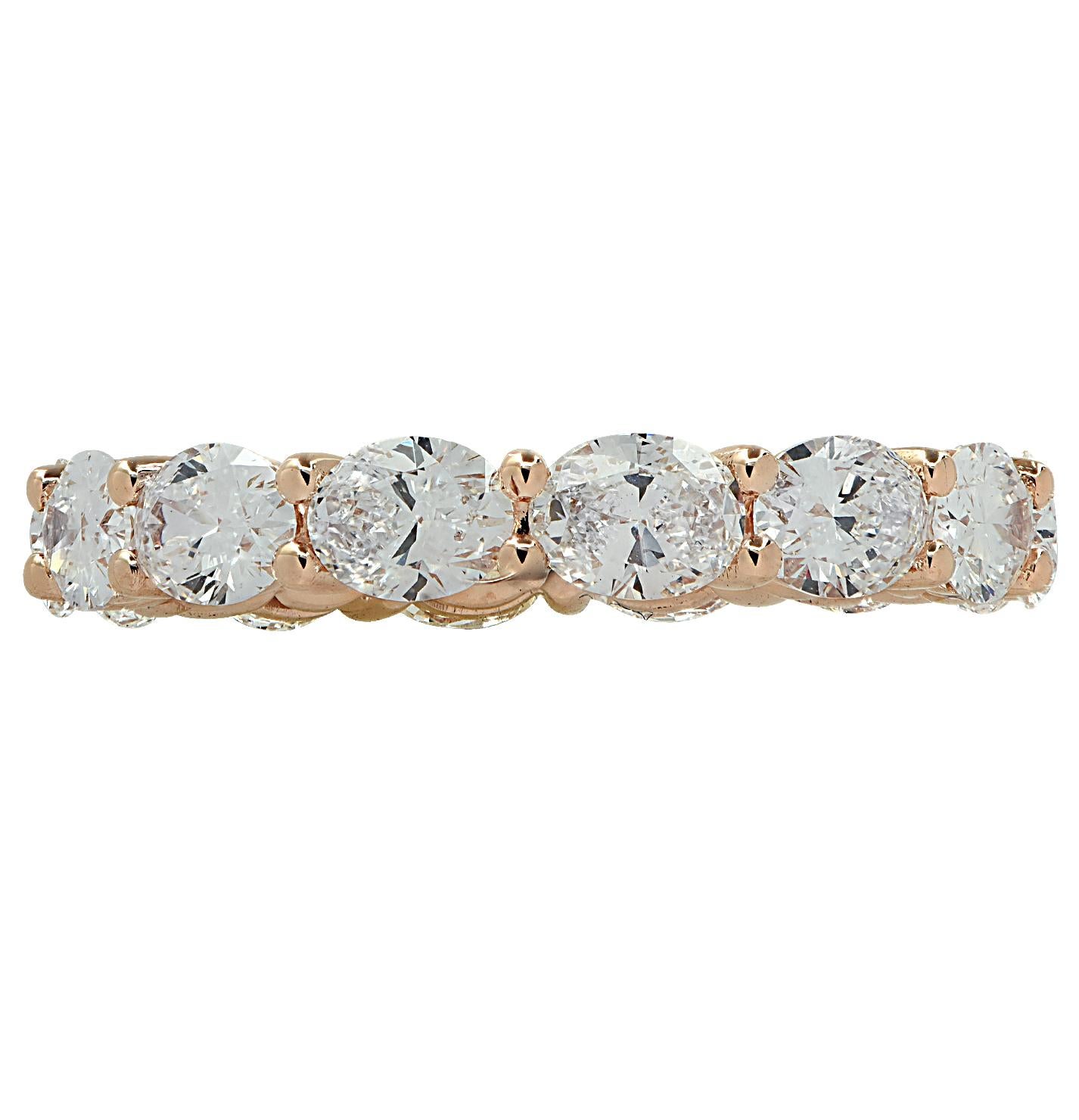 Stunning Vivid Diamonds Eat-West Eternity Band crafted in 18 karat Rose Gold, featuring 14 oval cut diamonds weighing 2.60 carats total, D-E color, VVS-VS clarity. These fine diamonds are seamlessly set, east-west, in a modern take on the classic