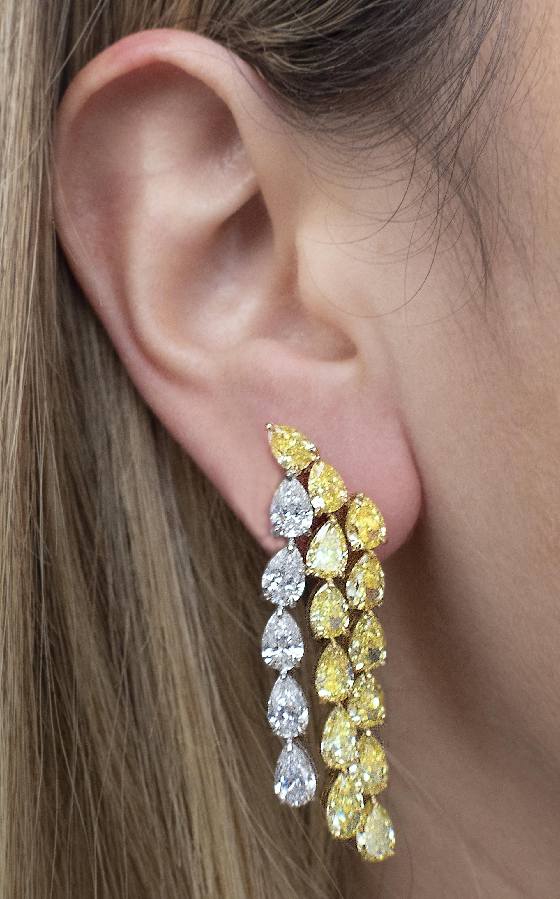 Captivating Vivid Diamonds platinum and 18k yellow gold dangle earrings, presenting a magnificent array of 36 GIA Certified, fancy intense yellow and white pear-shaped diamonds totaling 19.13 carats, with D-F color and VS1-SI1 clarity. These