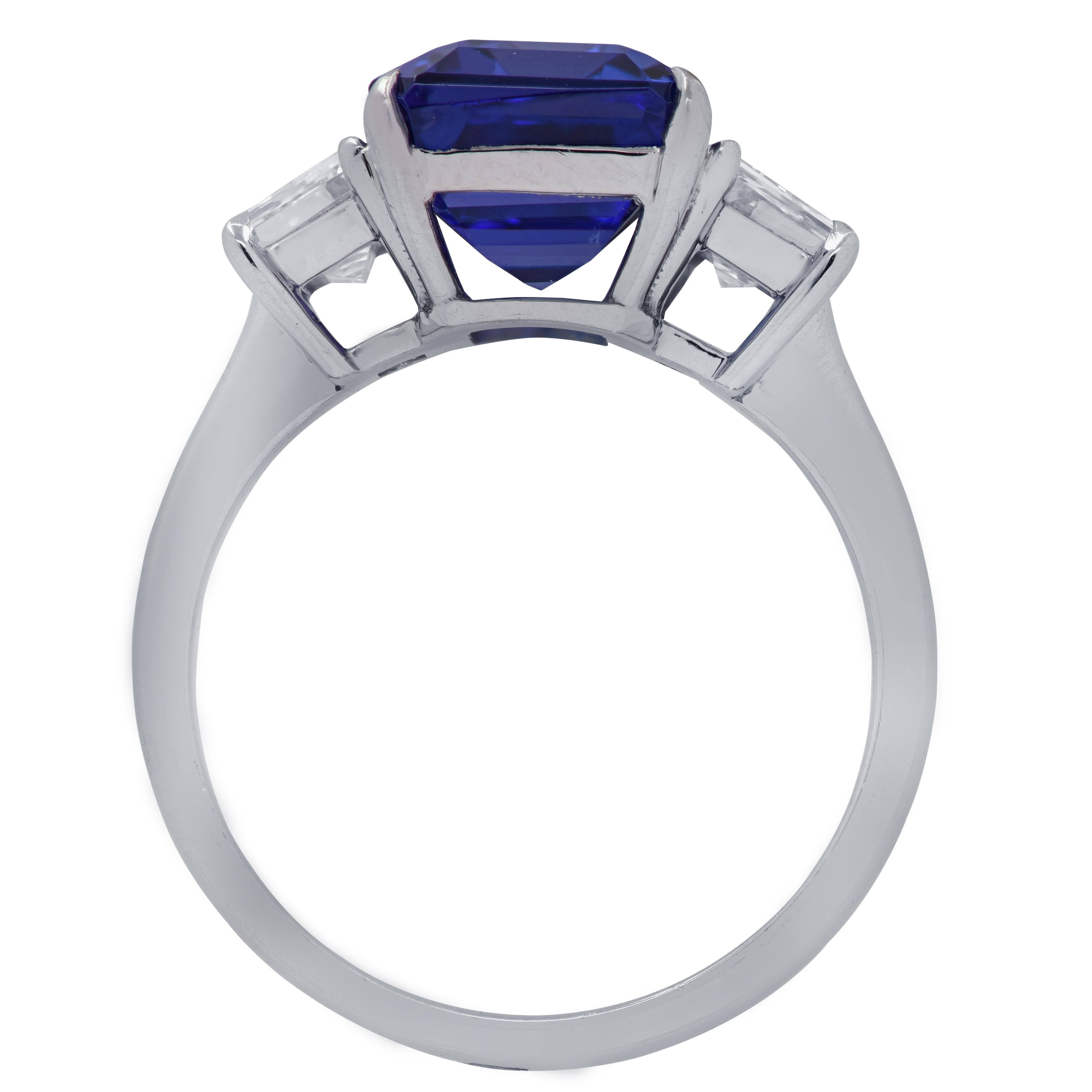 Spectacular Vivid Diamonds ring, handcrafted in Platinum featuring a 4.29 carat Emerald Cut Tanzanite adorned with 2 step cut trapezoid diamonds weighing .94 carats total, F color and VS clarity. The band of this stunning ring measures 2.2 mm 2.67