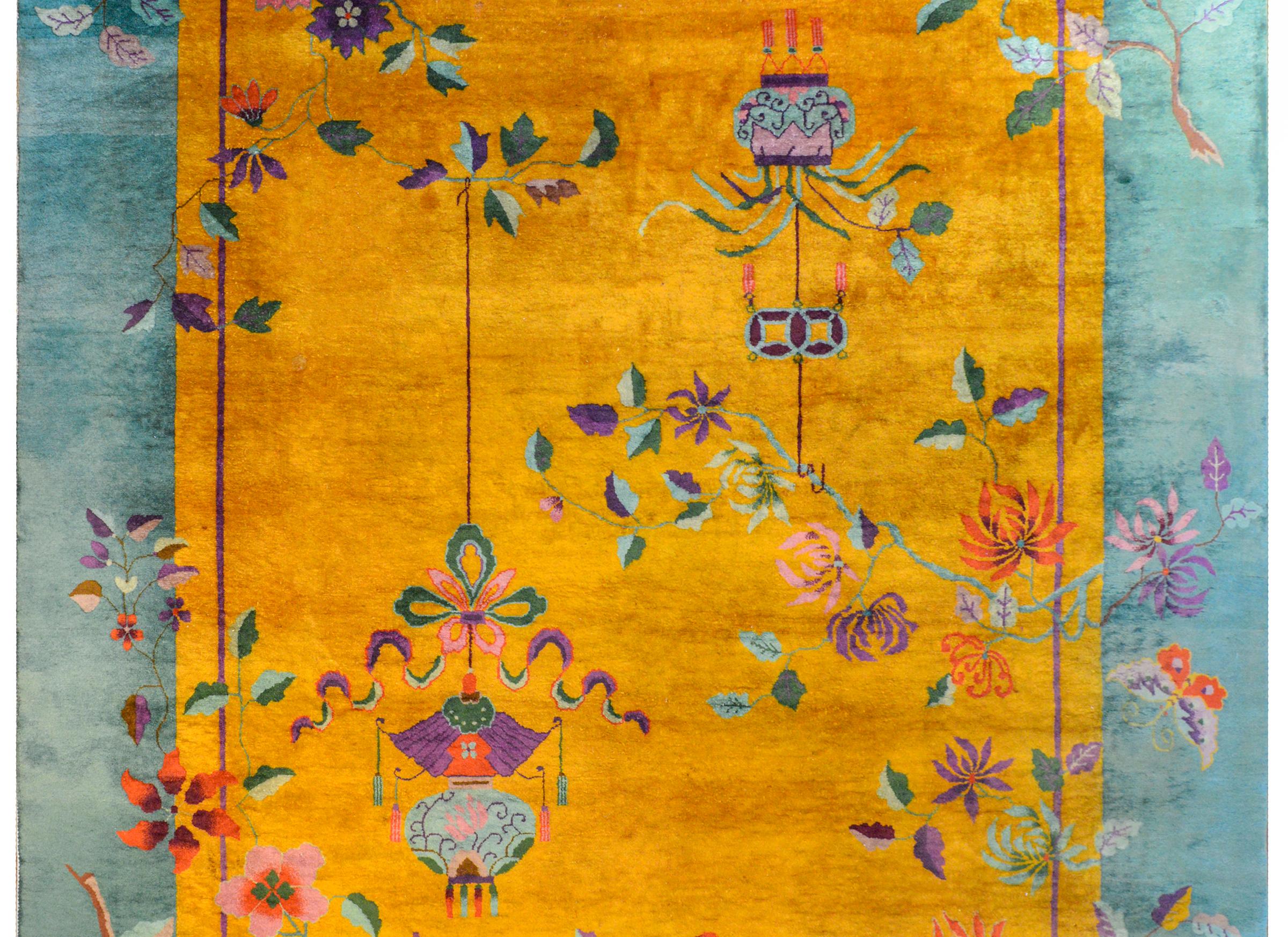A vivid early 20th century Chinese Art Deco rug with an incredible brilliant goldenrod field surrounded by a wide teal border and all overlaid with myriad auspicious flowers including chrysanthemums, peonies, and cherry blossoms with two potted