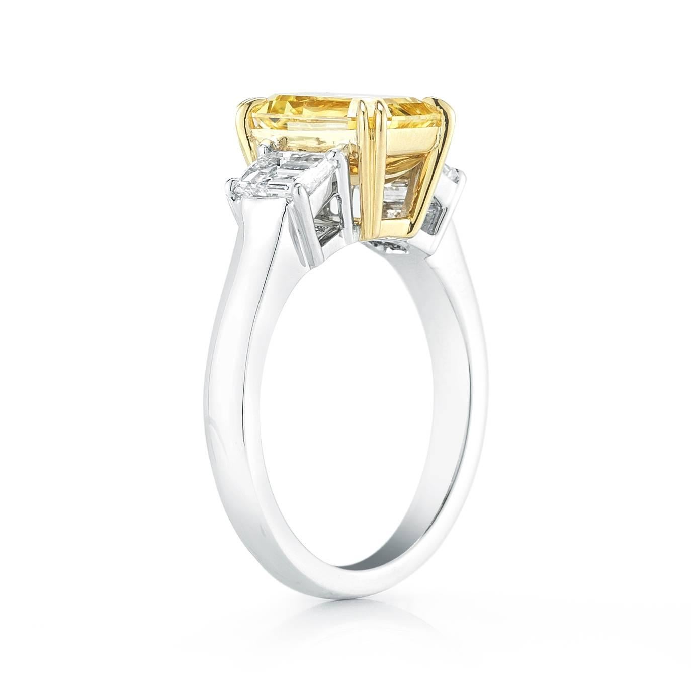  A 2.54 Ct Vivid Yellow Emerald cut Diamond set in Platinum and 18K  Yellow Gold  3 stone ring.  
Two matching emerald cut diamonds flank the center diamond  , weighing .86 Cts total, and are E color, and VS clarity. 
Vivid  is the highest grade and