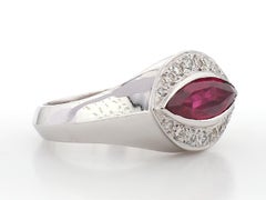 Anillo llamativo de platino con un rubí de corte marquesa muy brillante y un halo de diamantes redondos