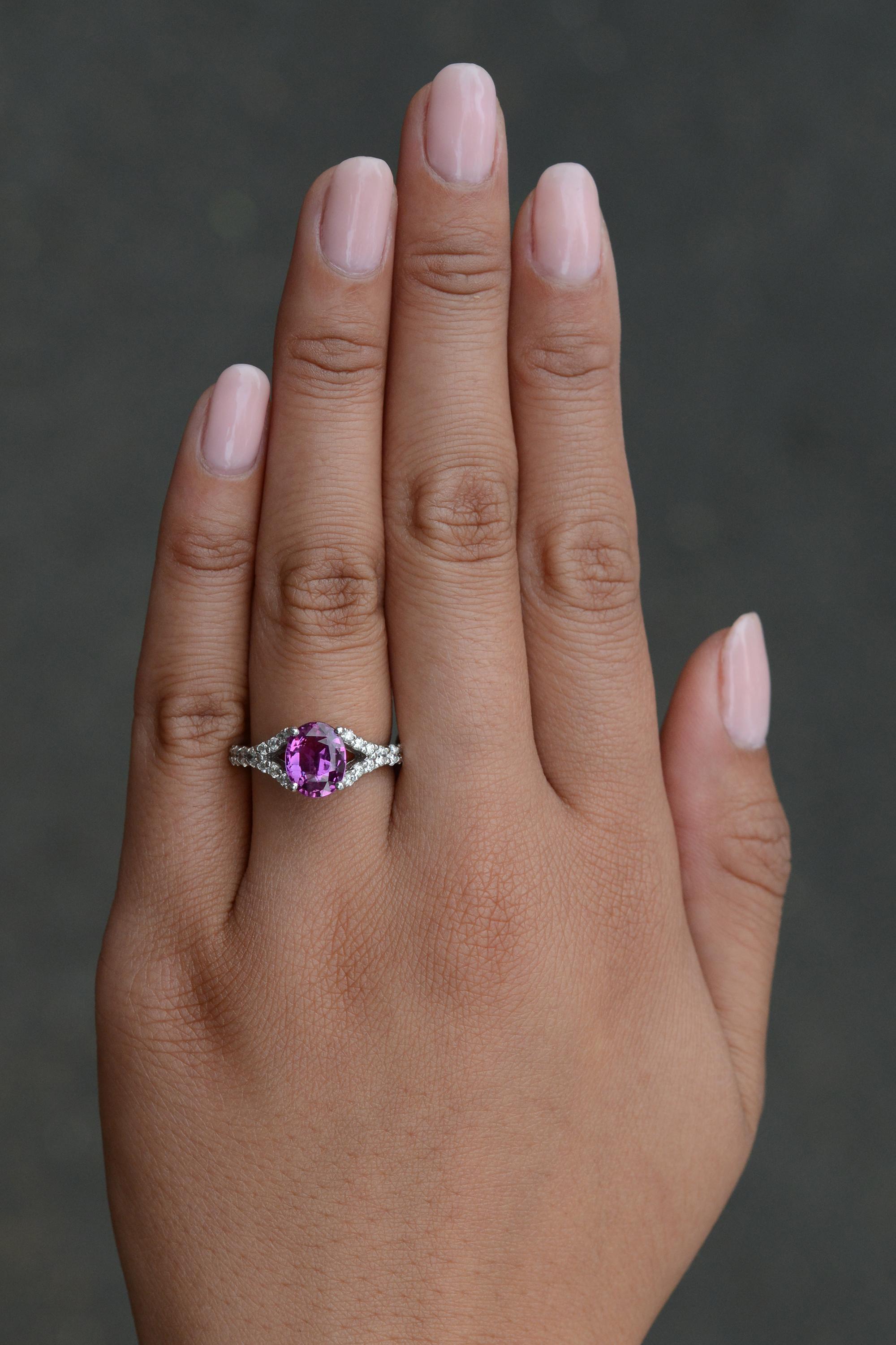 The vivid, bubblegum pink of this natural sapphire glows with an unmistakable luster and brilliance. The gemstone's deep saturation of color offers a striking contrast when paired with the fiery sparkle of the double diamond band, forming a wishbone