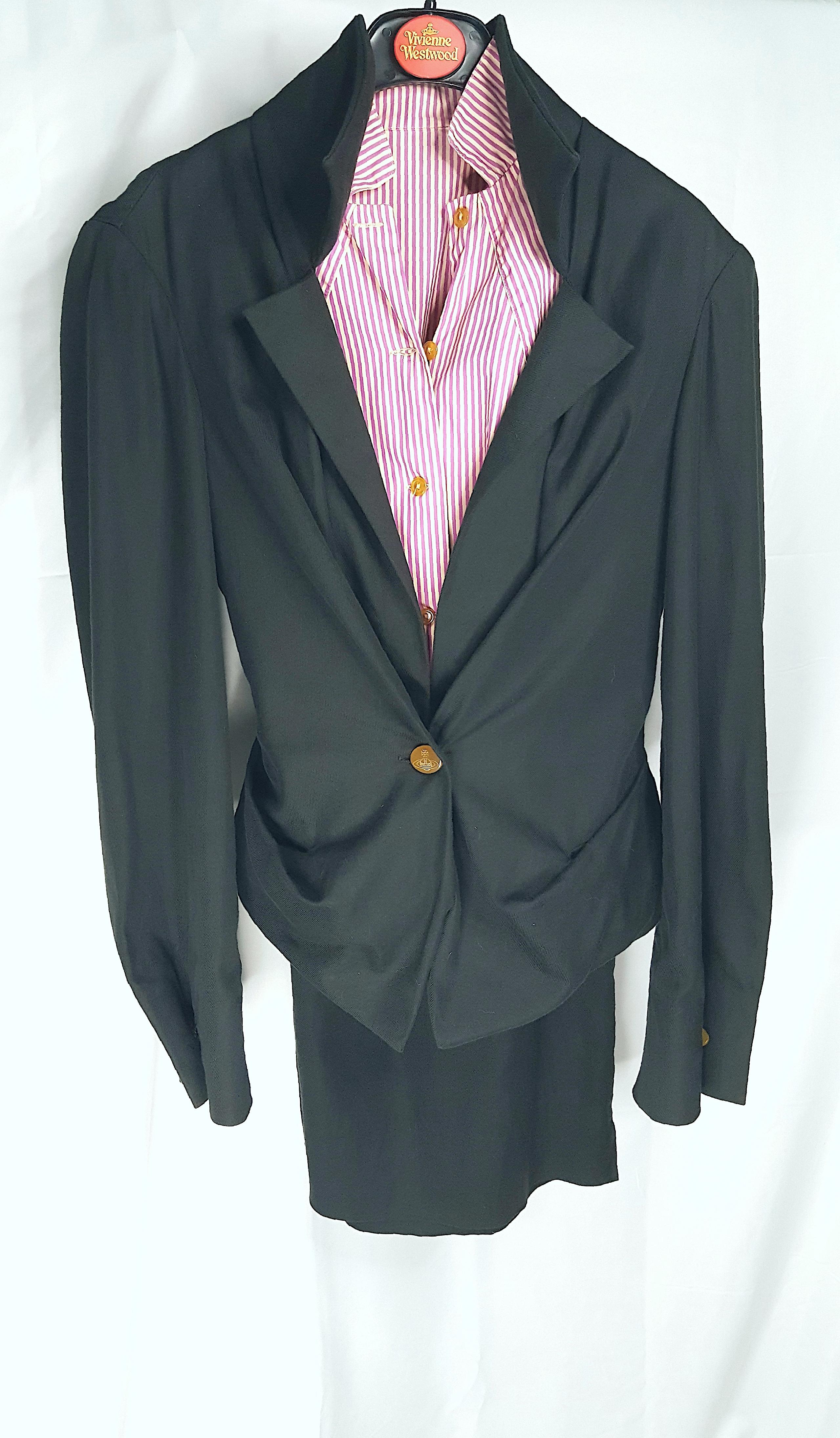 Pour le défilé printemps-été 1999 de la défunte créatrice britannique, cet ensemble en coton Vivienne Westwood, composé d'une veste noire de style corset, d'une jupe fendue assortie et d'une chemise boutonnée à rayures colorées, a été porté pour les