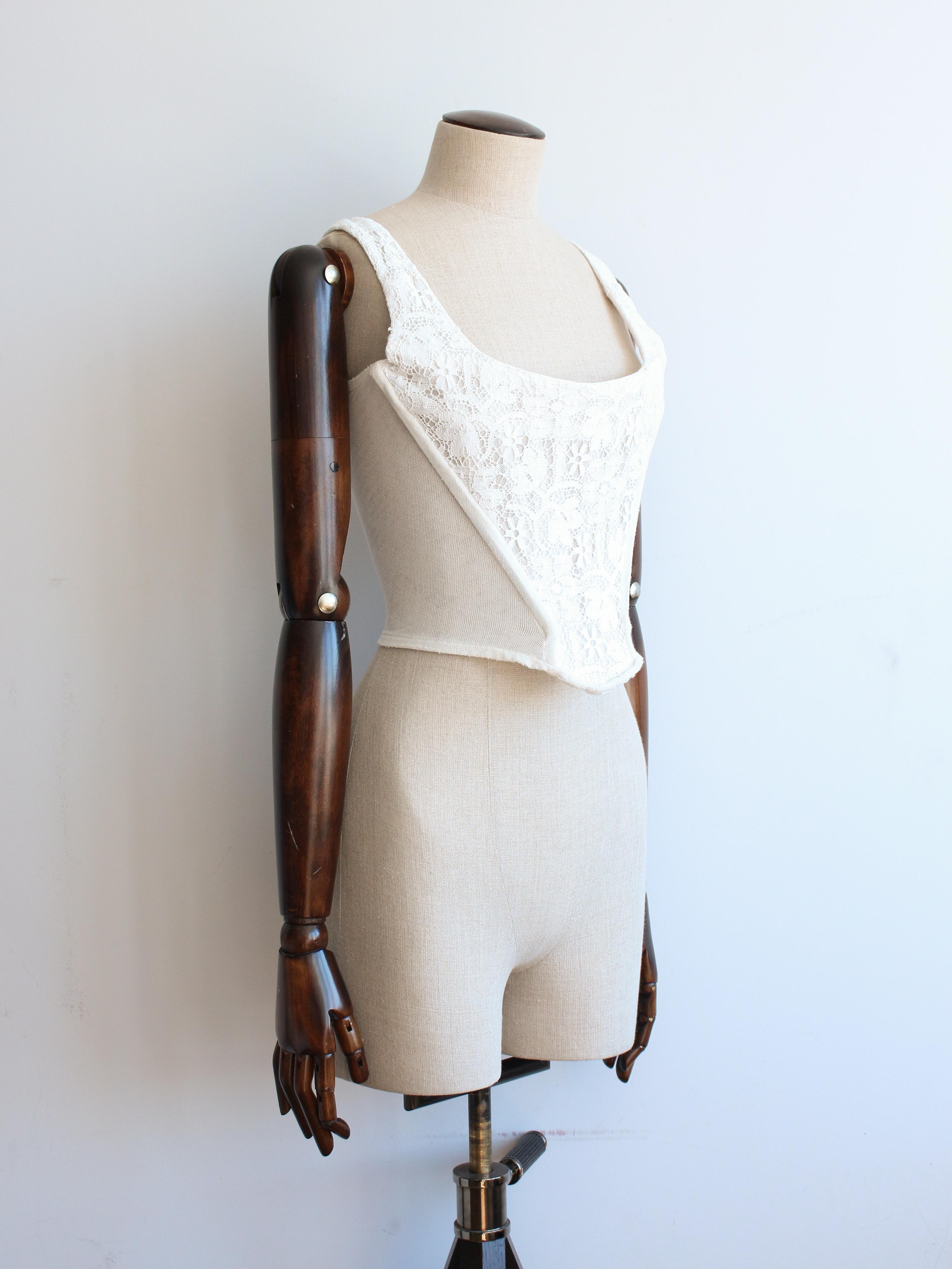 Vivienne Westwood Autumn/Winter 1994 white floral lace boned corset with mesh side panels.

Tagged size UK10.

In good condition, there is one small hole to the mesh as pictured and general wear throughout.