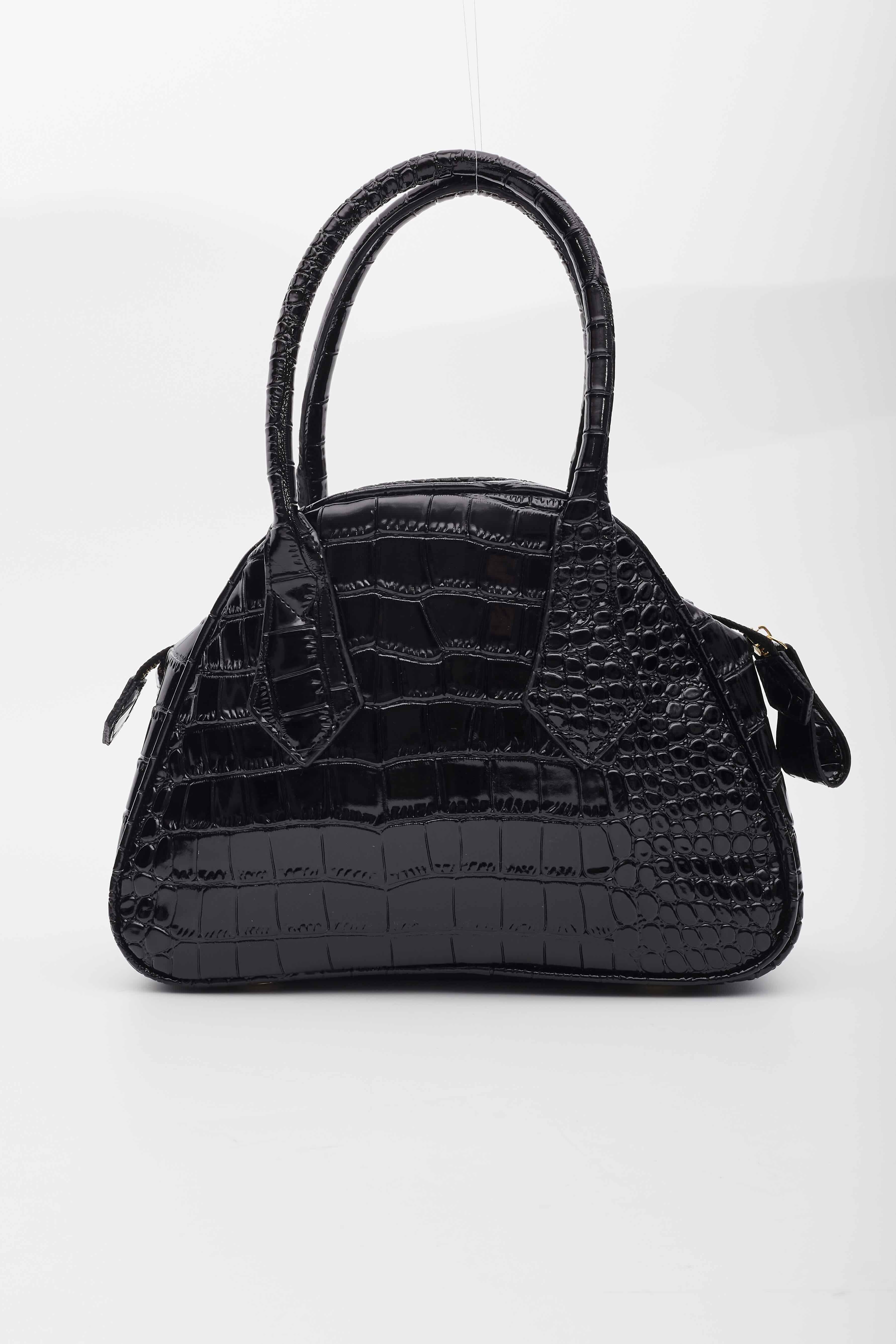 This bag features croc embossed faux leather, dual top handles, top zip closure with a large zipper tab, stripped cotton lining and a large orb on the front.

Color: Black
Material: Crock embossed vegan leather
Measures: Height 9” x Length 11” x
