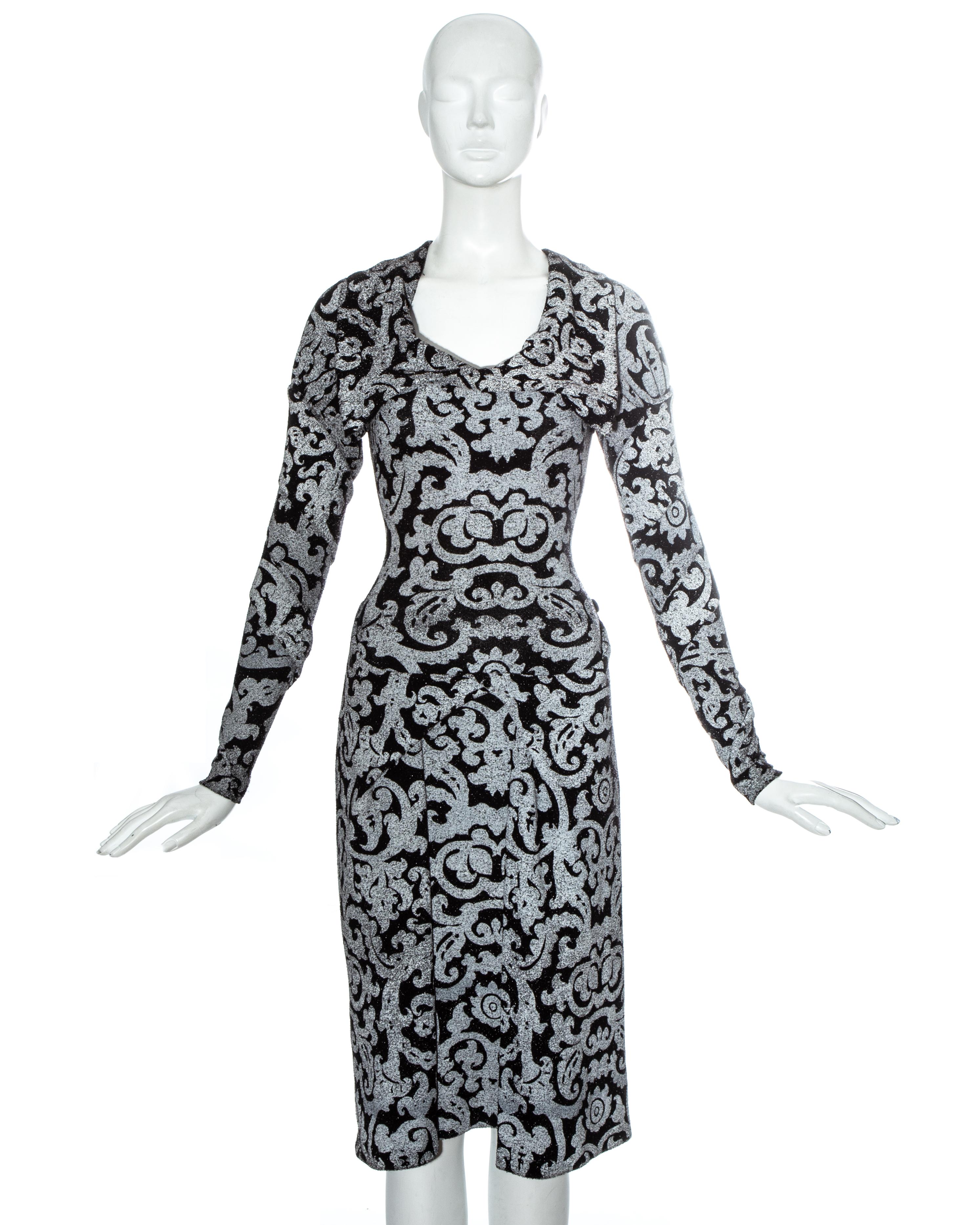 Vivienne Westwood figure hugging evening dress in black lurex with grey screen printed pattern. Bias cut sleeves, drapes and folds around hips with button fastening, two leg slits, side zip fastening, pointed collar and criss-cross panels around