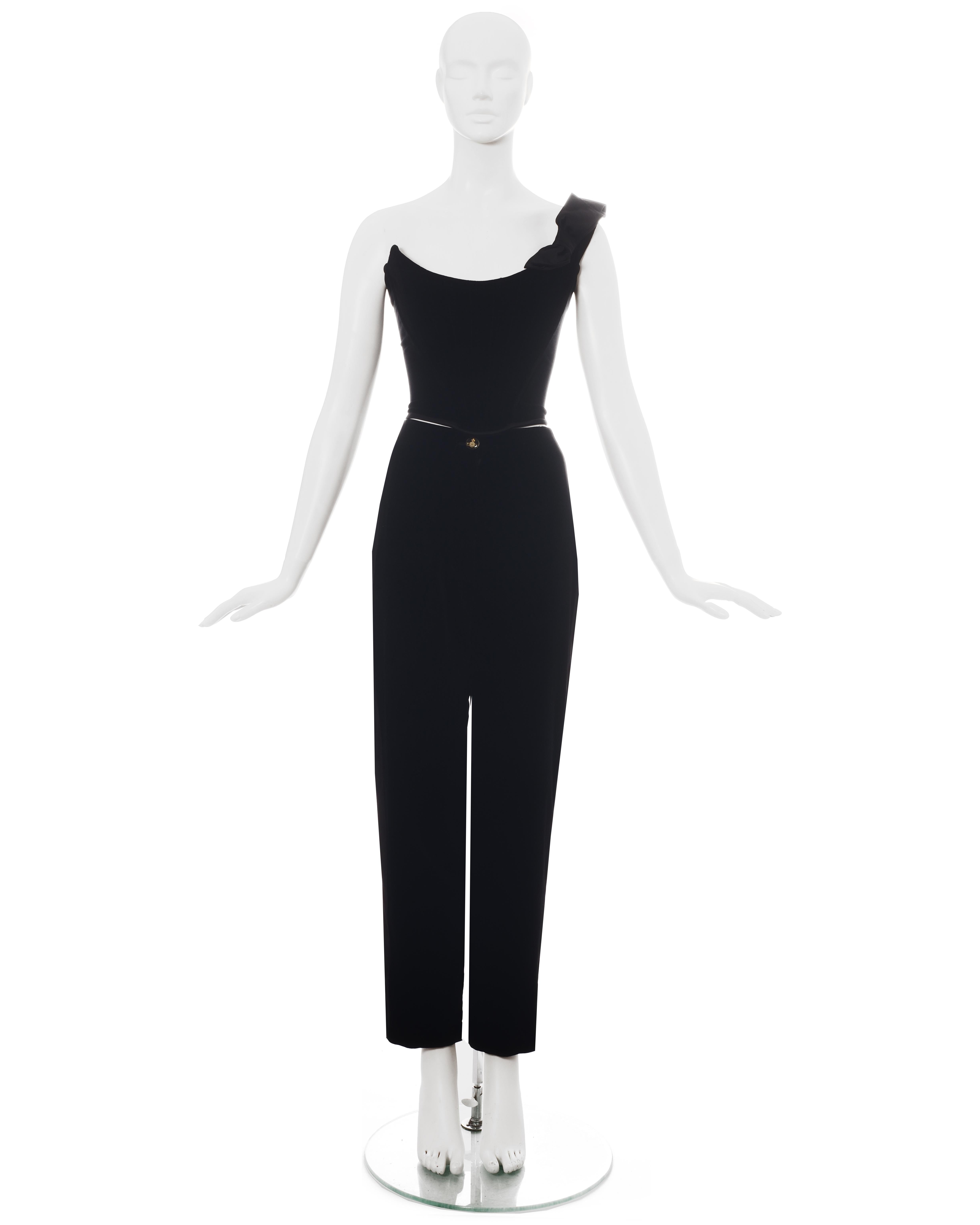Vivienne Westwood black velvet pant suit comprising: velvet bustier corset with one shoulder strap and large satin bow; matching tuxedo pants with satin side panels and orb button closure.

Fall-Winter 1996