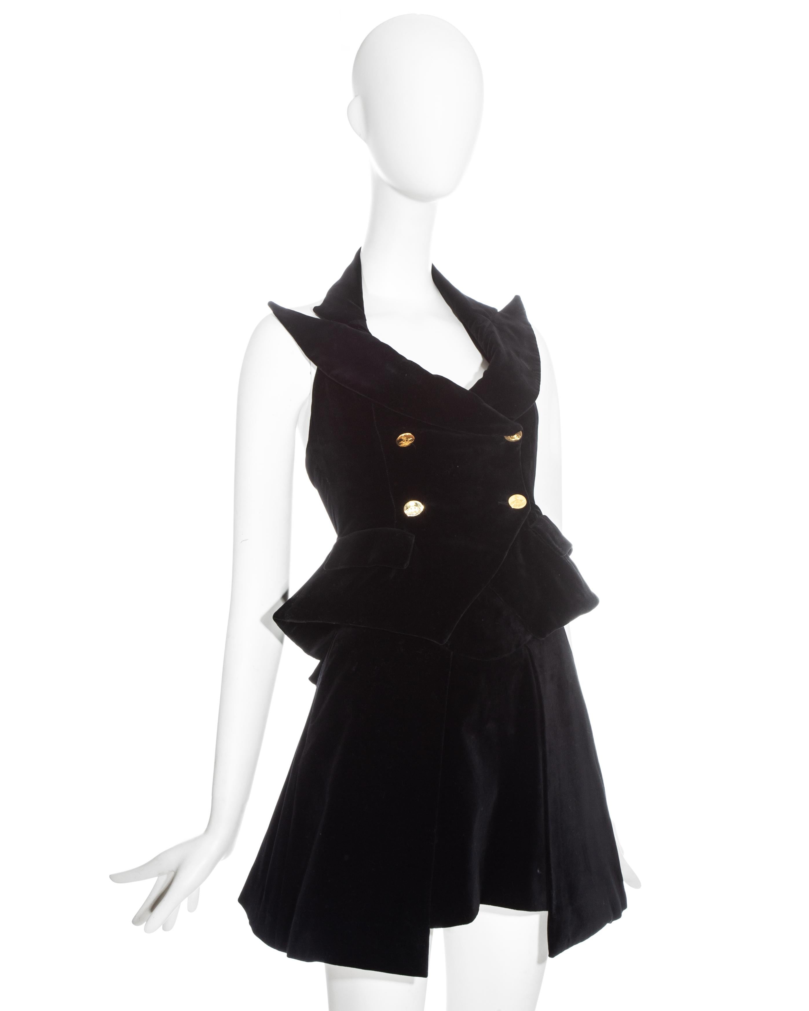 Chaleco de terciopelo negro Vivienne Westwood con cuello halter, botones dorados y grandes solapas de pico. Se vende con falda a juego de talle alto y dos bolsillos laterales. 

Primavera-Verano 1995