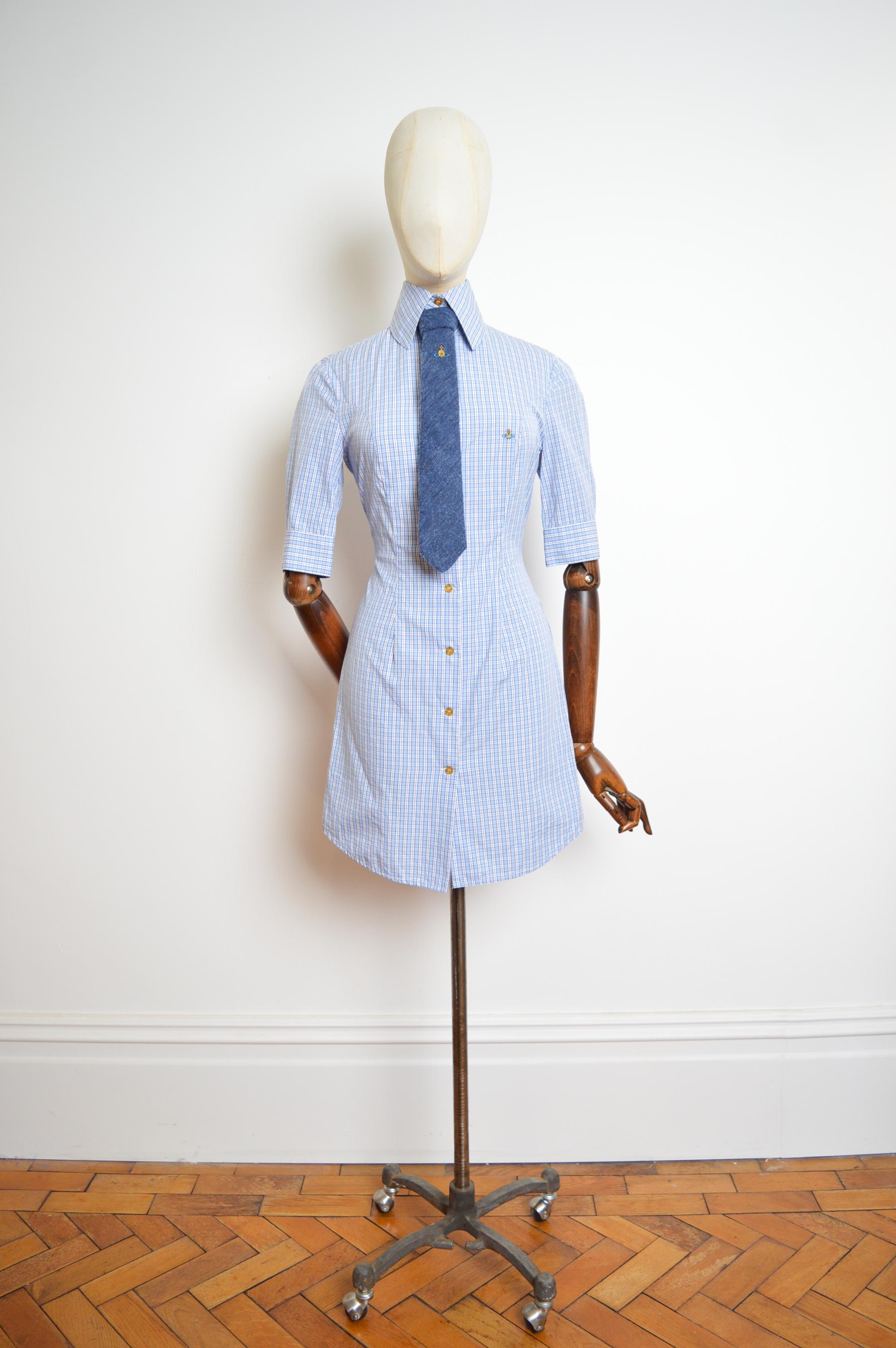 A Chic, elegantly cut Vivienne Westwood shirt dress circa 1994, crafted from Blue and white checked cotton with 3/4 long sleeves, fitted silhouette, buttons down the front, orb embroidered detail and High collar !  

Vivienne Westwood Wool Tie is