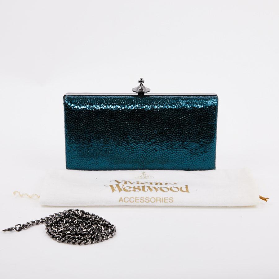 Vivienne Westwood python-effect clutch.
Elegant pouch in blue python-effect leather, carried by hand or on the shoulder using a removable strap.
The jewelry is made of ruthenium effect metal. The interior is lined in satin fabric with a floral