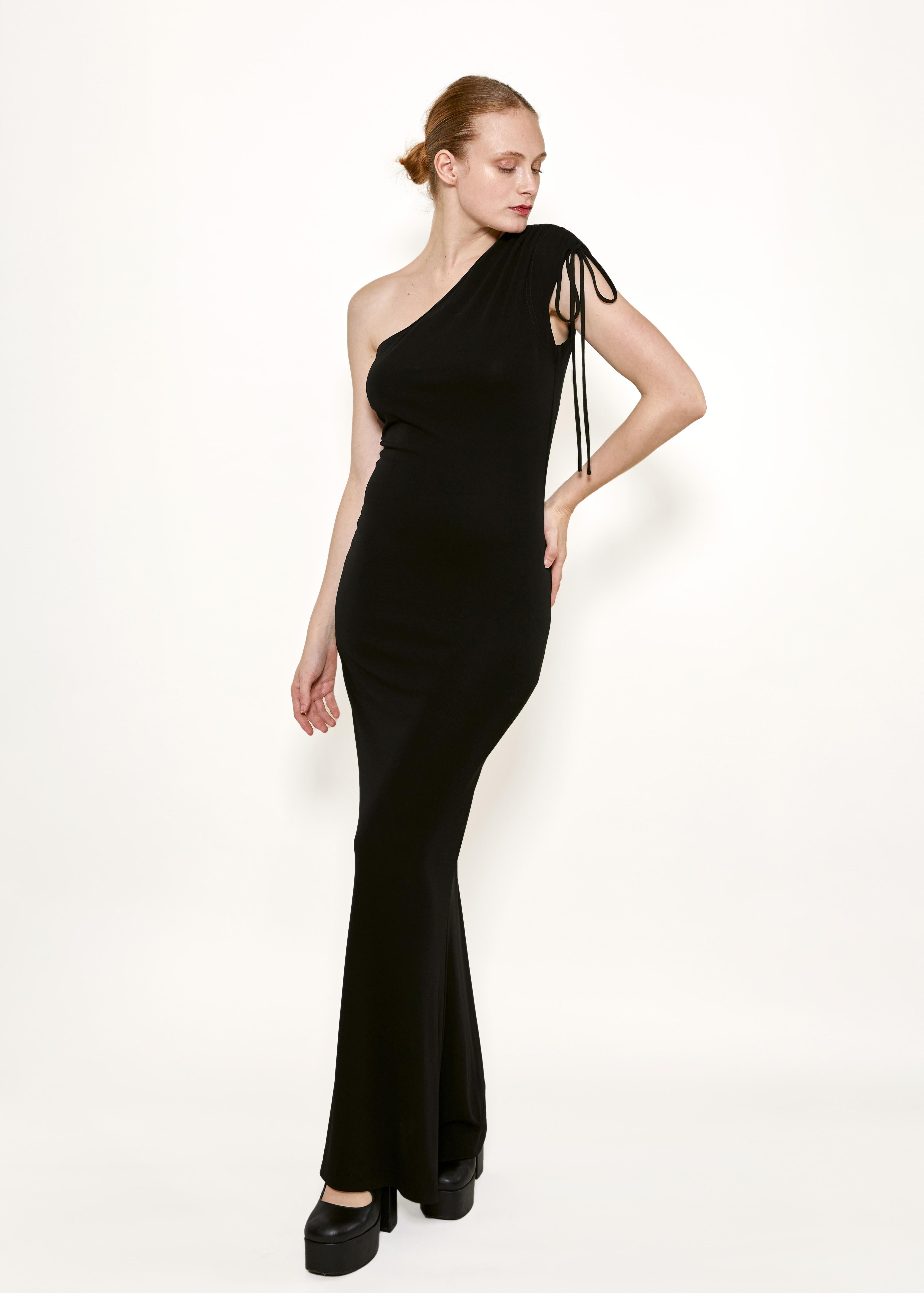 Indulge in luxury with the Vivienne Westwood Gold Label Black Jersey One Shoulder Dress. This couture piece features a drawstring shoulder for a unique touch, while its maxi length adds grace and elegance. The jersey fabric brings a stretchiness to