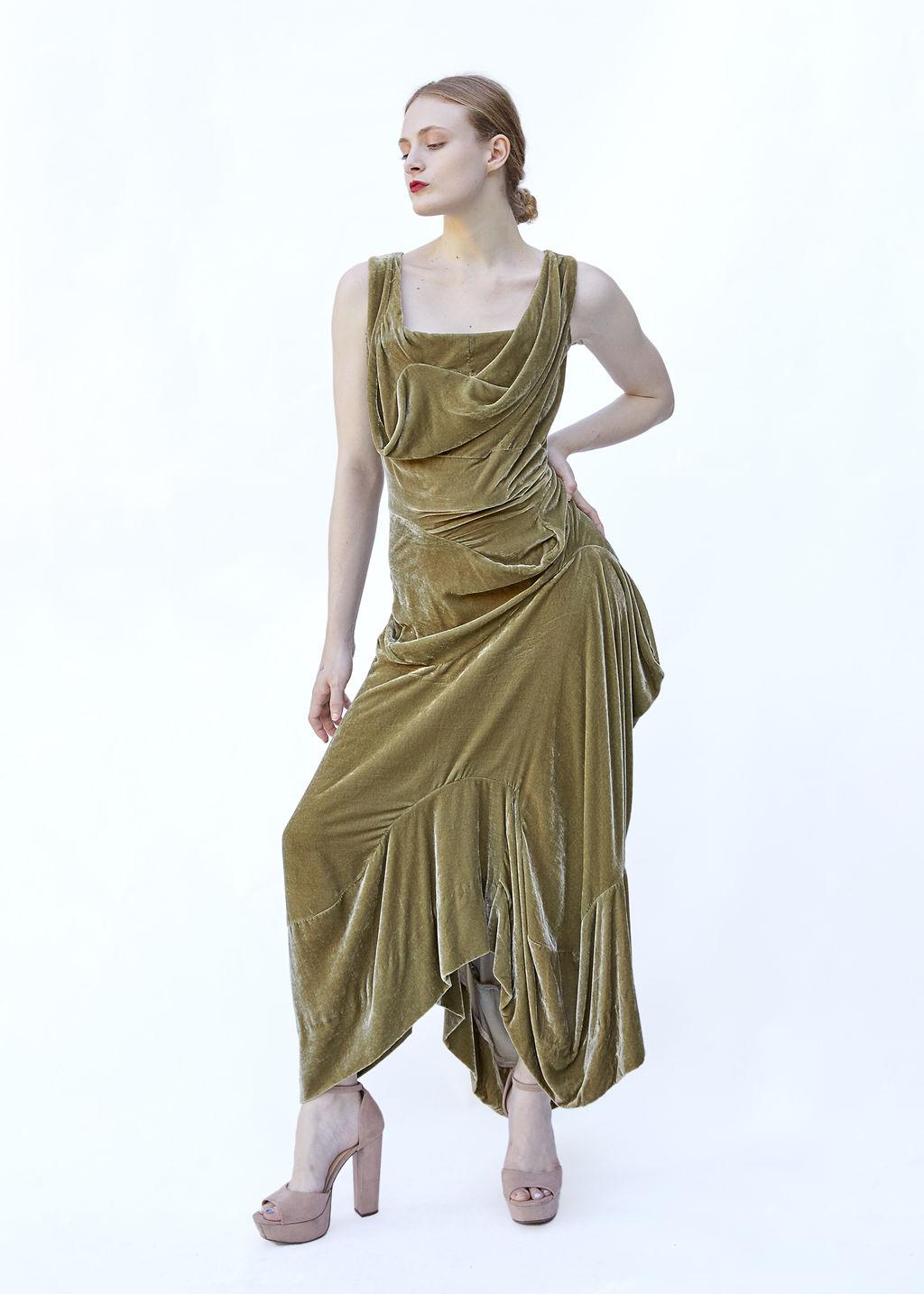 Embrace high-fashion elegance with this luxurious Vivienne Westwood Gold Label gown, crafted from sumptuous moss-colored velvet. Known for her iconic silhouettes, Westwood's corseted design accentuates the waist and celebrates feminine curves, while