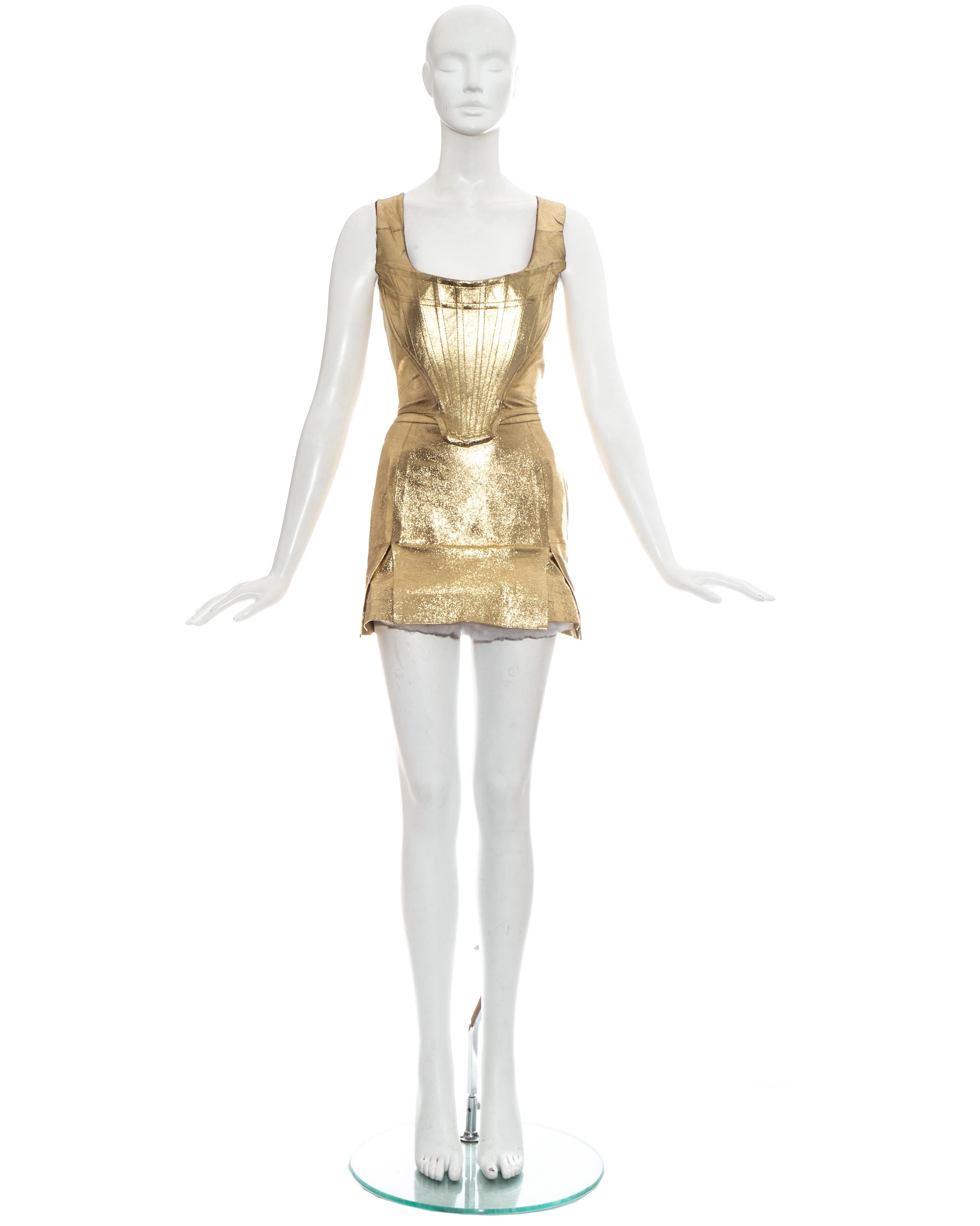 Vivienne Westwood; gold leather corset and skirt ensemble. Corset with internal boning, designed to cinch the waist and push the breasts up. High waisted mini skirt designed backwards with vent at the front and tulle petticoat. 

Seen on Madonna in