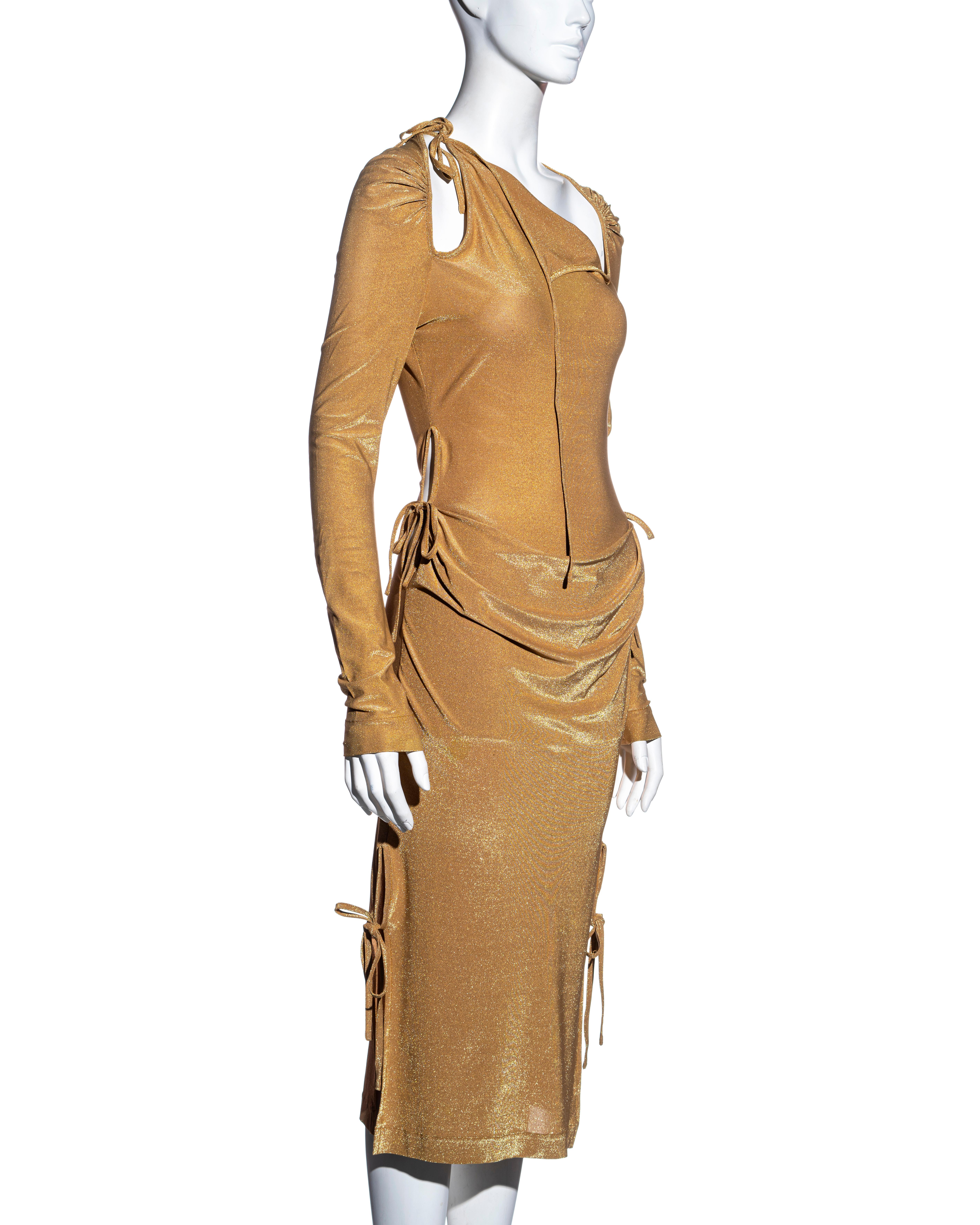 ▪ Vivienne Westwood gold stretch lurex evening dress
▪ Multiple cut-outs with tie fastenings which can be styled in various ways 
▪ Ruched detail at the stomach and shoulders
▪ Long fitted sleeves 
▪ Calf length skirt 
▪ 63% Viscose, 20% Polyester,