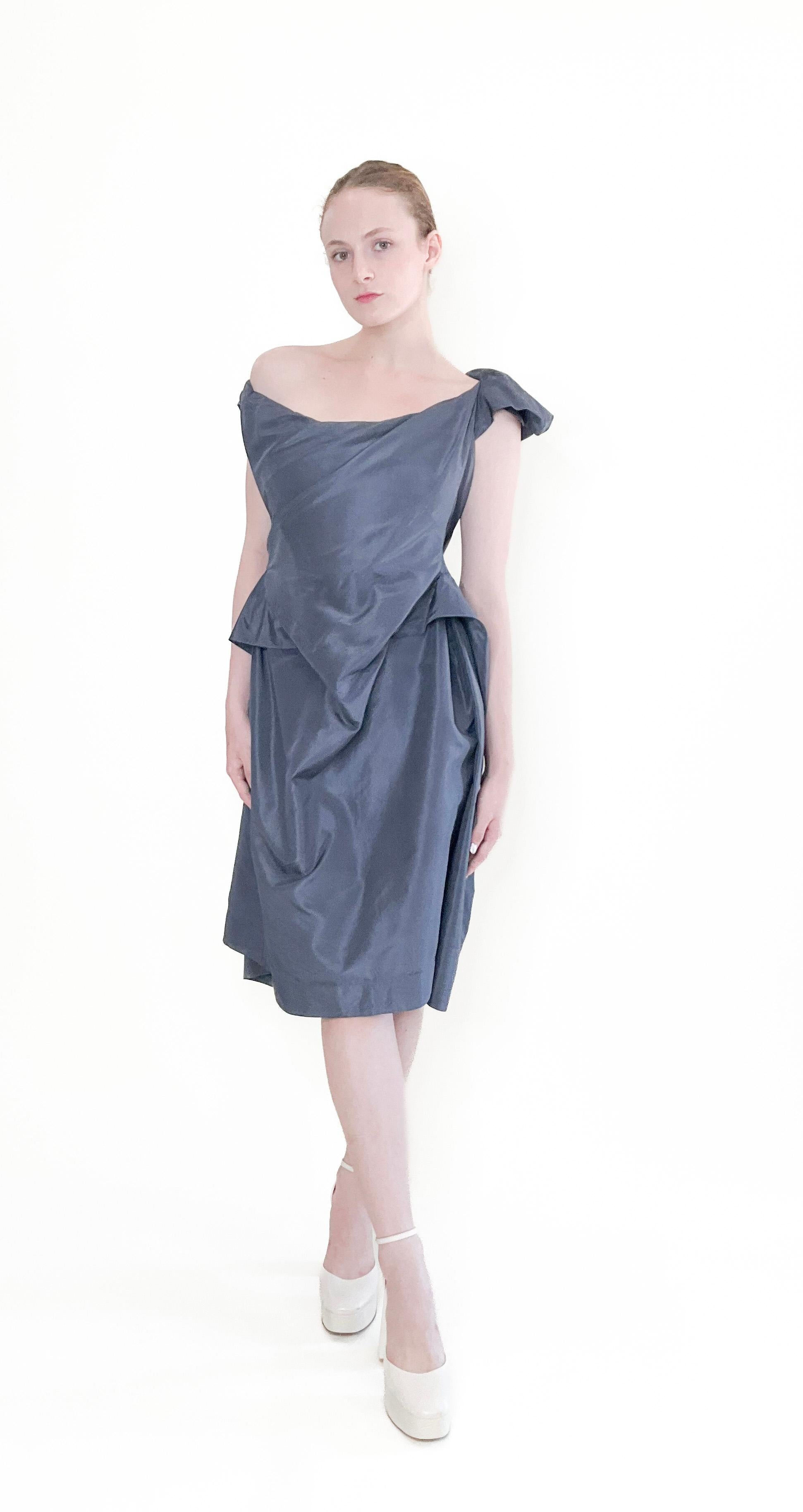 Expertly designed and beautifully crafted, the Vivienne Westwood Granite Silk corset Cocktail Dress is the perfect choice for any stylish occasion. Made from luxurious graphite blue silk taffeta, this signature corseted dress boasts an off shoulder