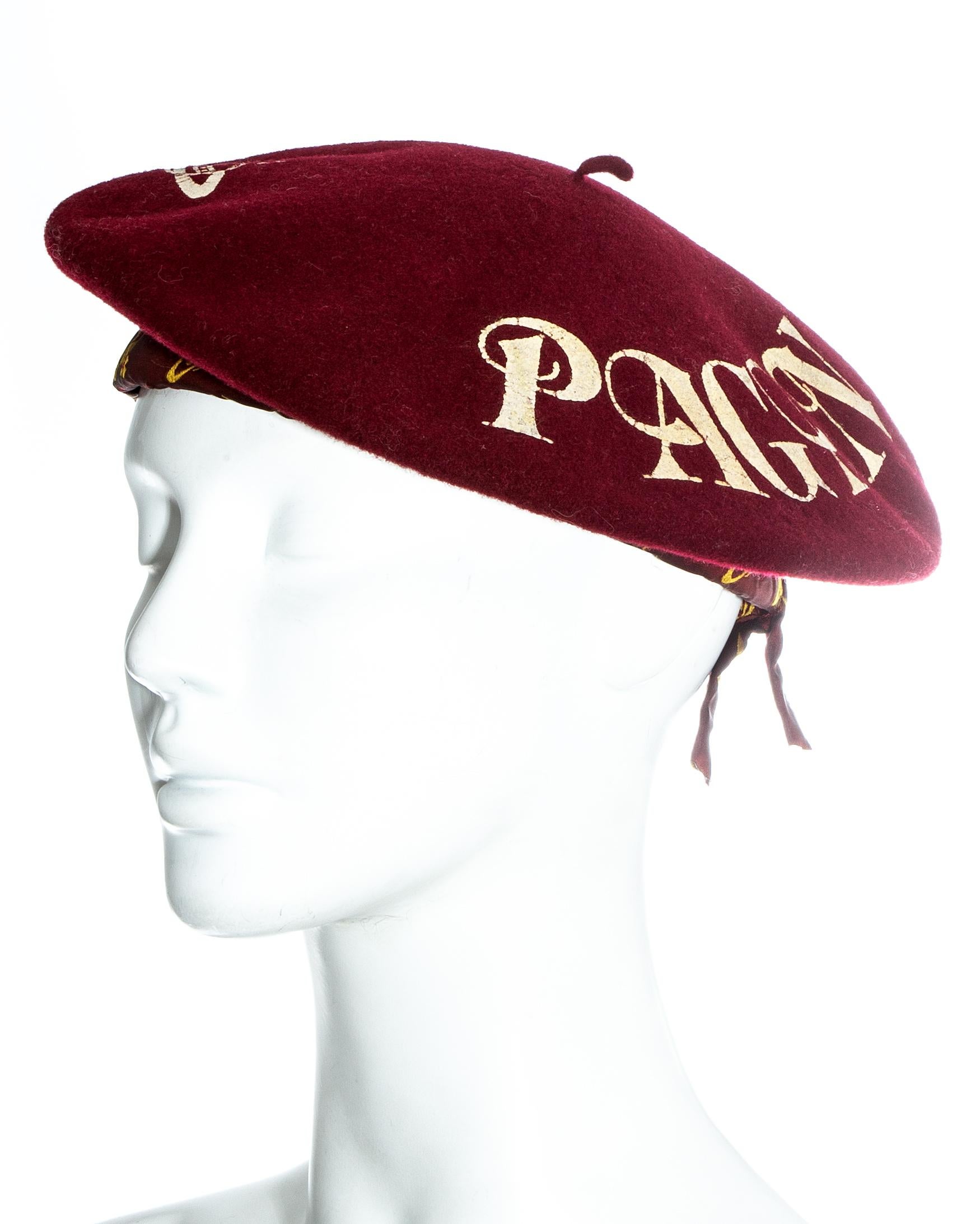 Rare Vivienne Westwood red wool beret with gold leaf 'PAGAN KISS' and signature Orb logo. Made for the 'Choice' tour with Sara Stockbridge in 1988.  

Pagan I, Spring-Summer 1988