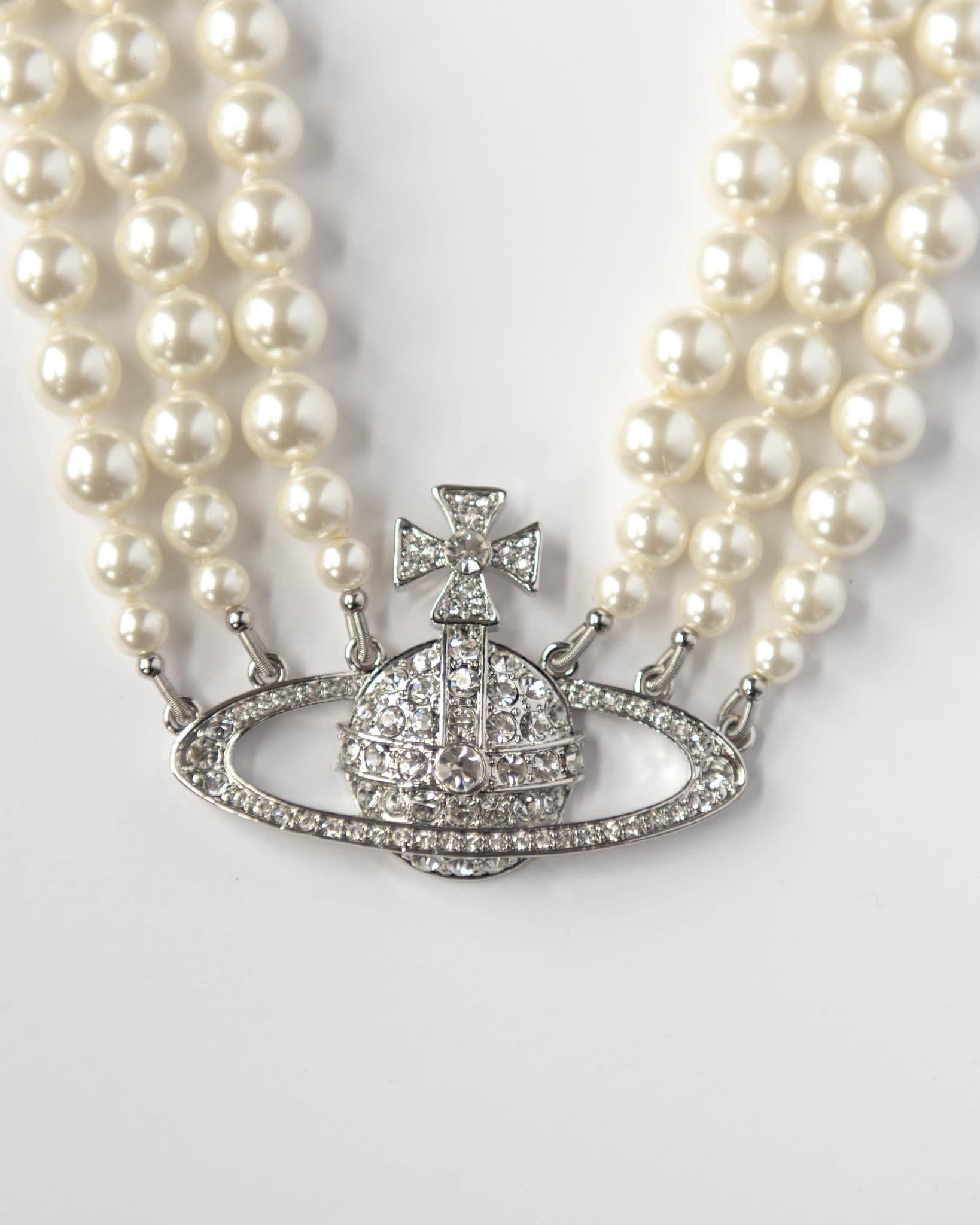 The iconic Vivienne Westwood pearl collection from decades ago is revisited. The sliver-tone three row pearl choker is hard knotted with rows of Swarovski pearls and set with the encrusted Orb at the centre. It’s deigned to hug the neck in true