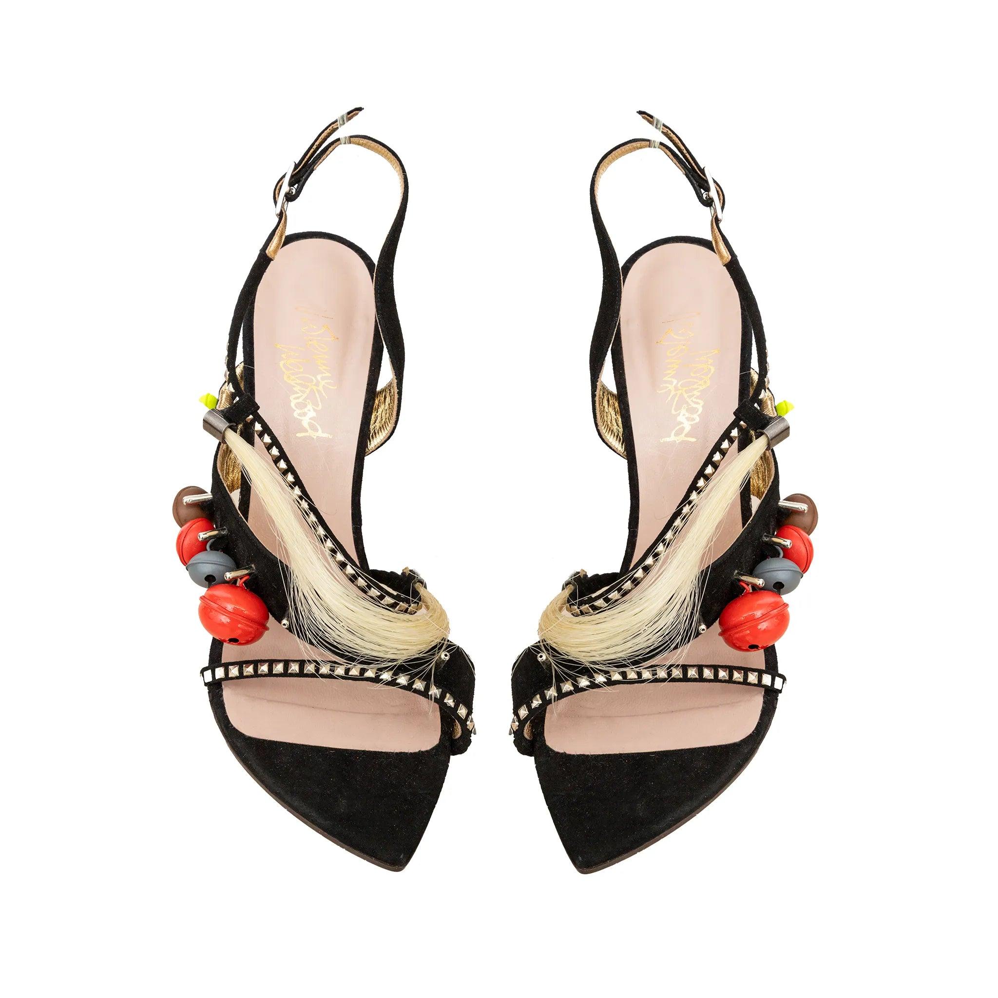 Voodoo-Sandalen von Vivienne Westwood, aus schwarzem Wildleder mit beigen Fadenakzenten, Glöckchen und Nieten. Ein mutiges, vom Punk inspiriertes Statement mit kantigem, ikonischem Flair.
 Inklusive: Staubbeutel. 
 Bemerkungen: Es gibt einige