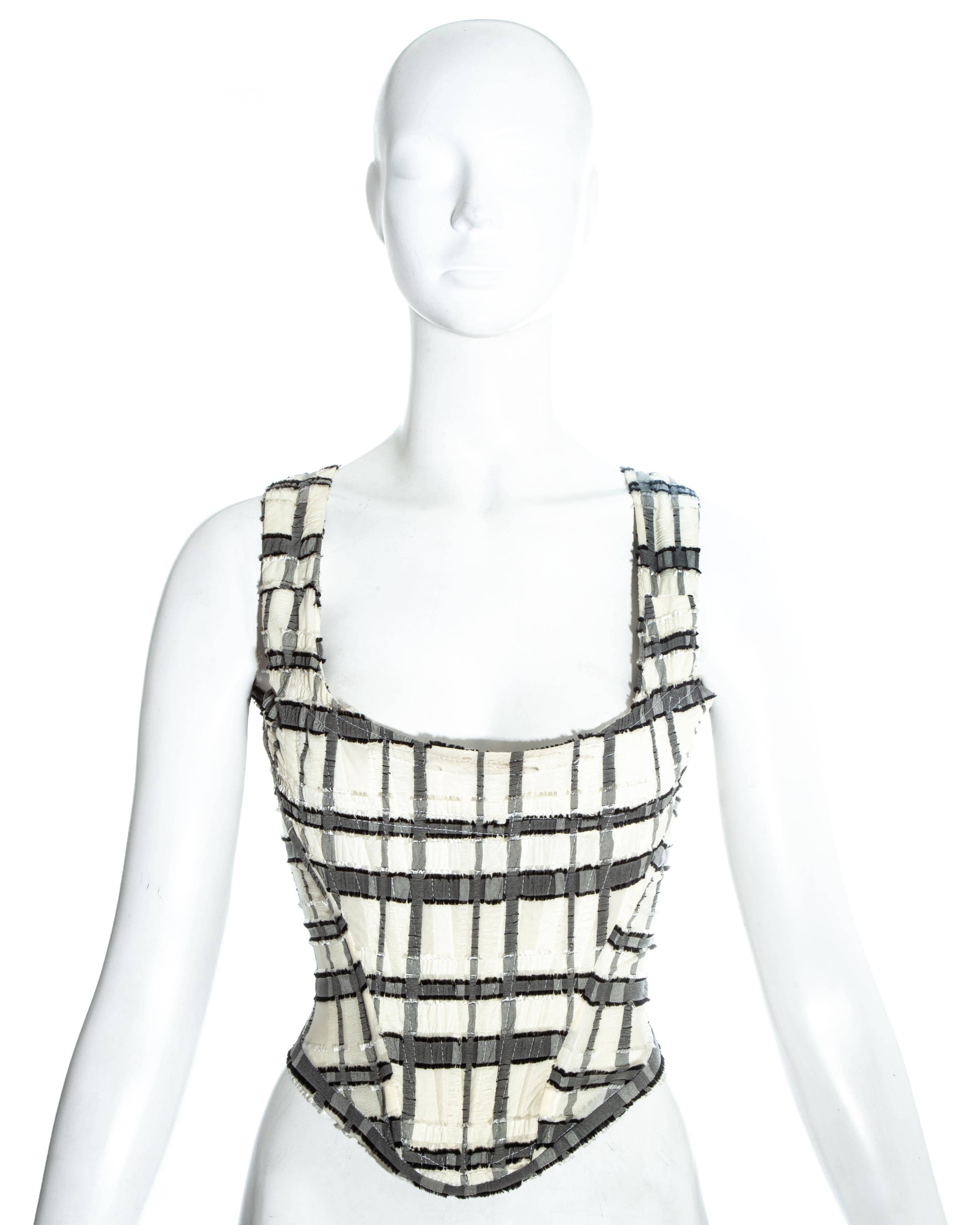 Weiß und grau kariertes Korsett von Vivienne Westwood, das die Taille einschnürt und die Brüste nach oben drückt.

Frühjahr-Sommer 1994