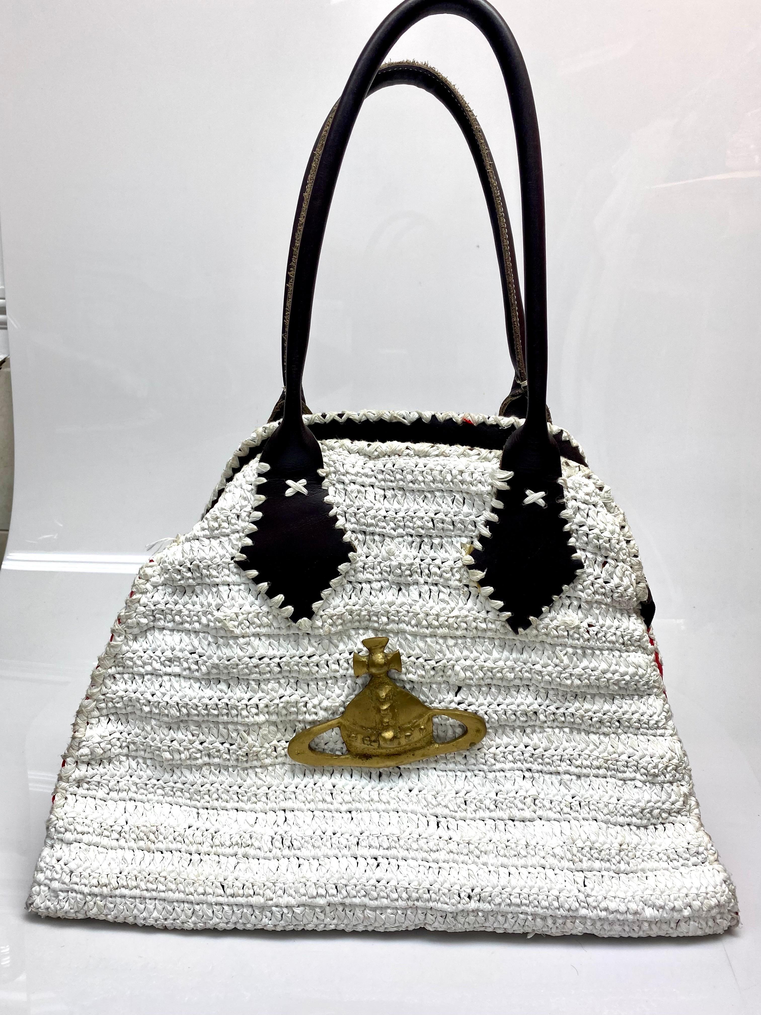 Vivienne Westwood White Crochet Bag. This oversized bag by Vivienne Westwood is the perfect luxury tote to carry all of your necessities. The piece features crotchet detailing, red leather sides, brown leather handles with white stitching, zipper