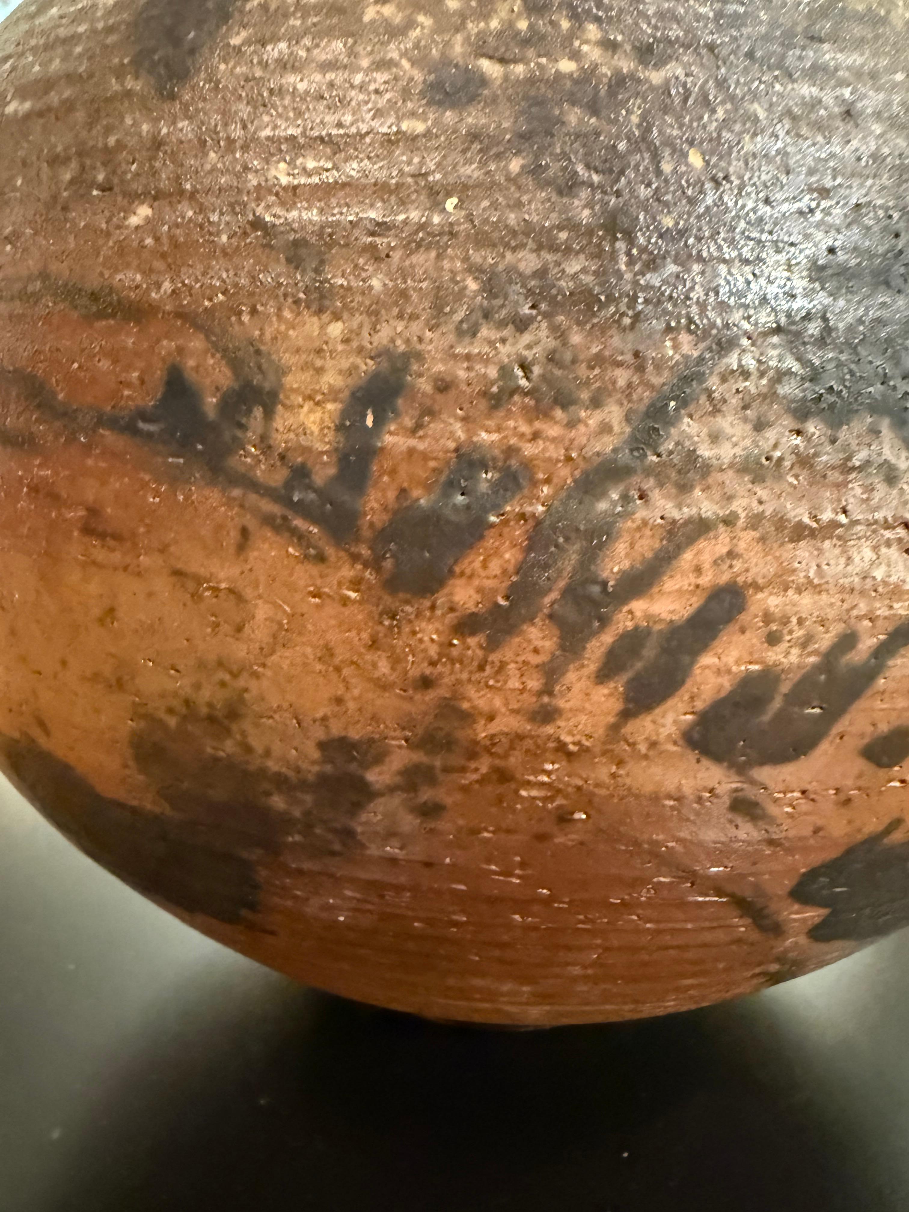 Diese große, handgedrehte Steinzeugkugel ist erdig, taktil und kraftvoll zurückhaltend. Sie ist ein Beispiel für die ikonische Ästhetik von Vivika und Otto Heino - zwei der einflussreichsten Persönlichkeiten der amerikanischen Studiokeramik. Die