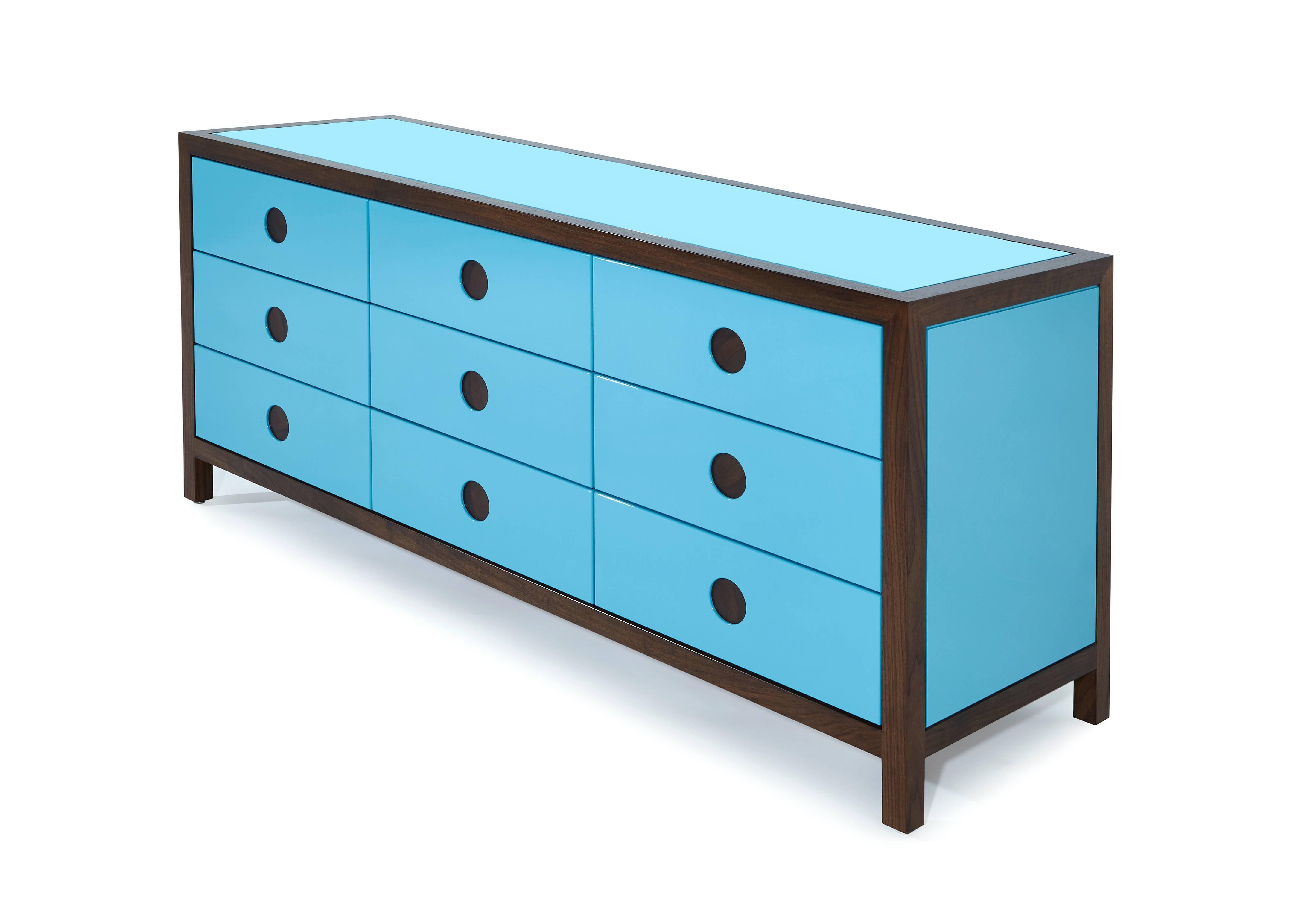 Mixing midcentury shapes with glossy lacquer, richly stained walnut, and inset circular walnut details, this low dresser with six push to open drawers is the perfect mix of function and high style.