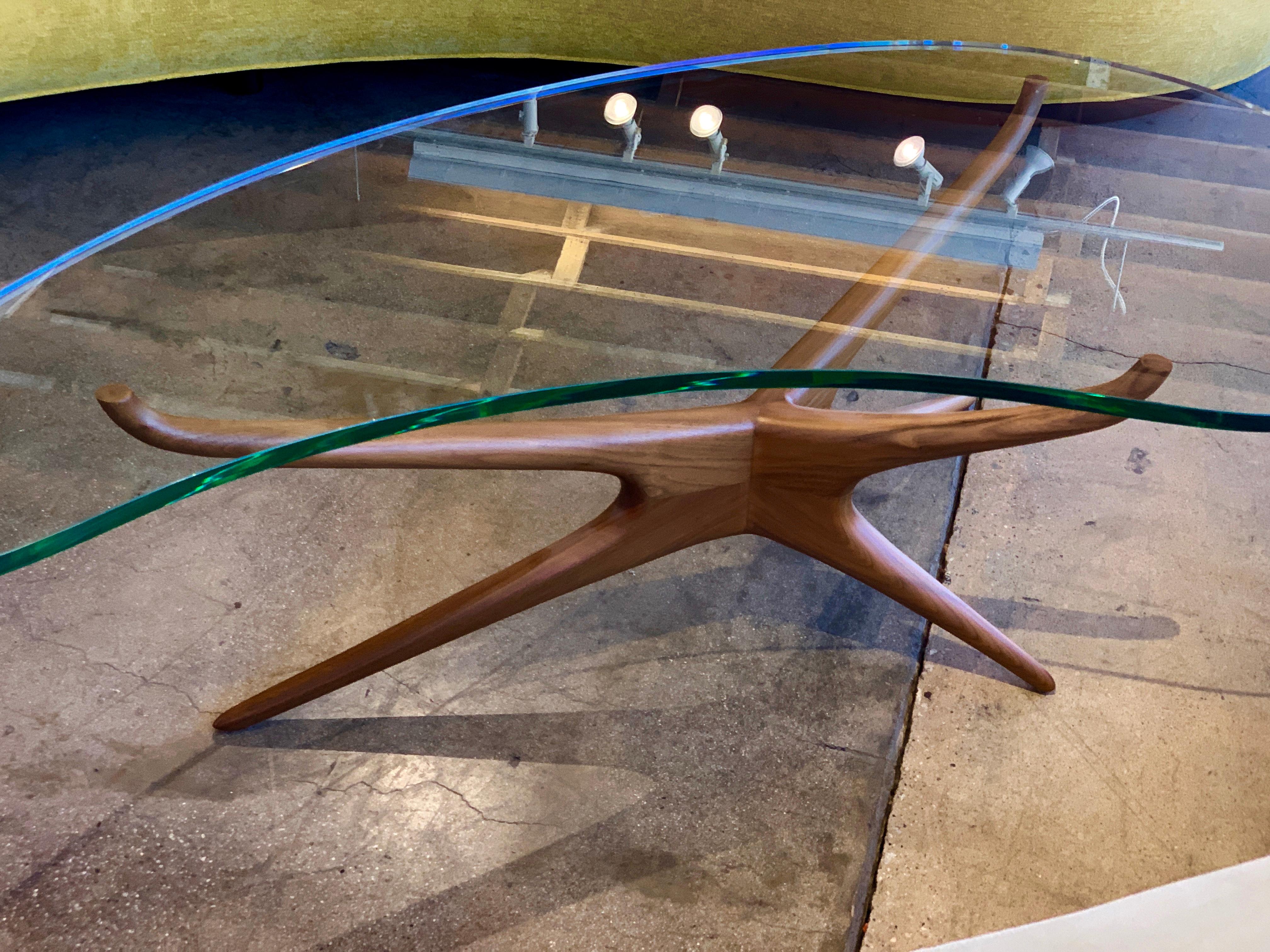 A nice newer bi-morphic glass top coffee table designed by Vladimir Kagan. This table was purchased from Holly Hunt. It is a few years old and is in very good condition with only some minor marks to the glass and wood base.