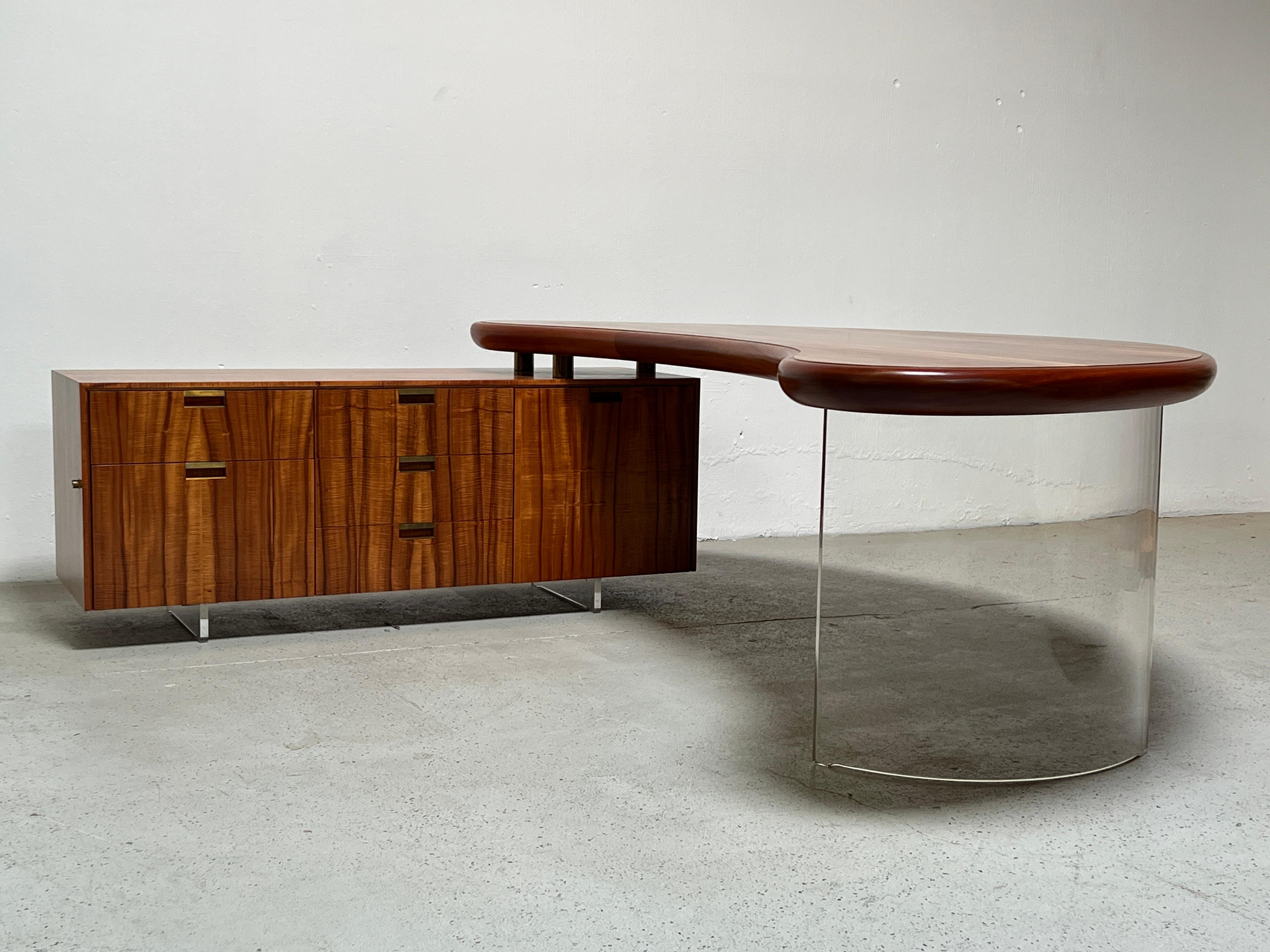  A large, executive desk designed by Vladimir Kagan. The Koa wood boomerang desk top floats on a curved lucite base. The return with bronze hardware and lucite runners as well.  Beautifully restored and ready for use. 